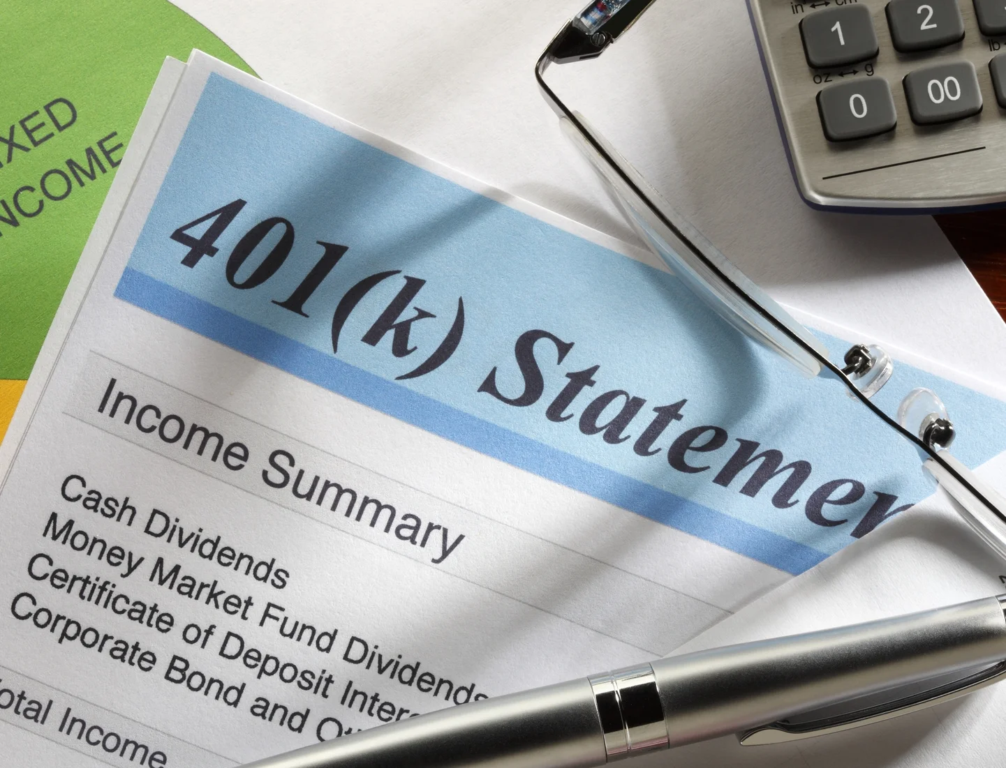 Financial documents and a calculator on a desk, including a 401(k) statement, glasses, and a pen.