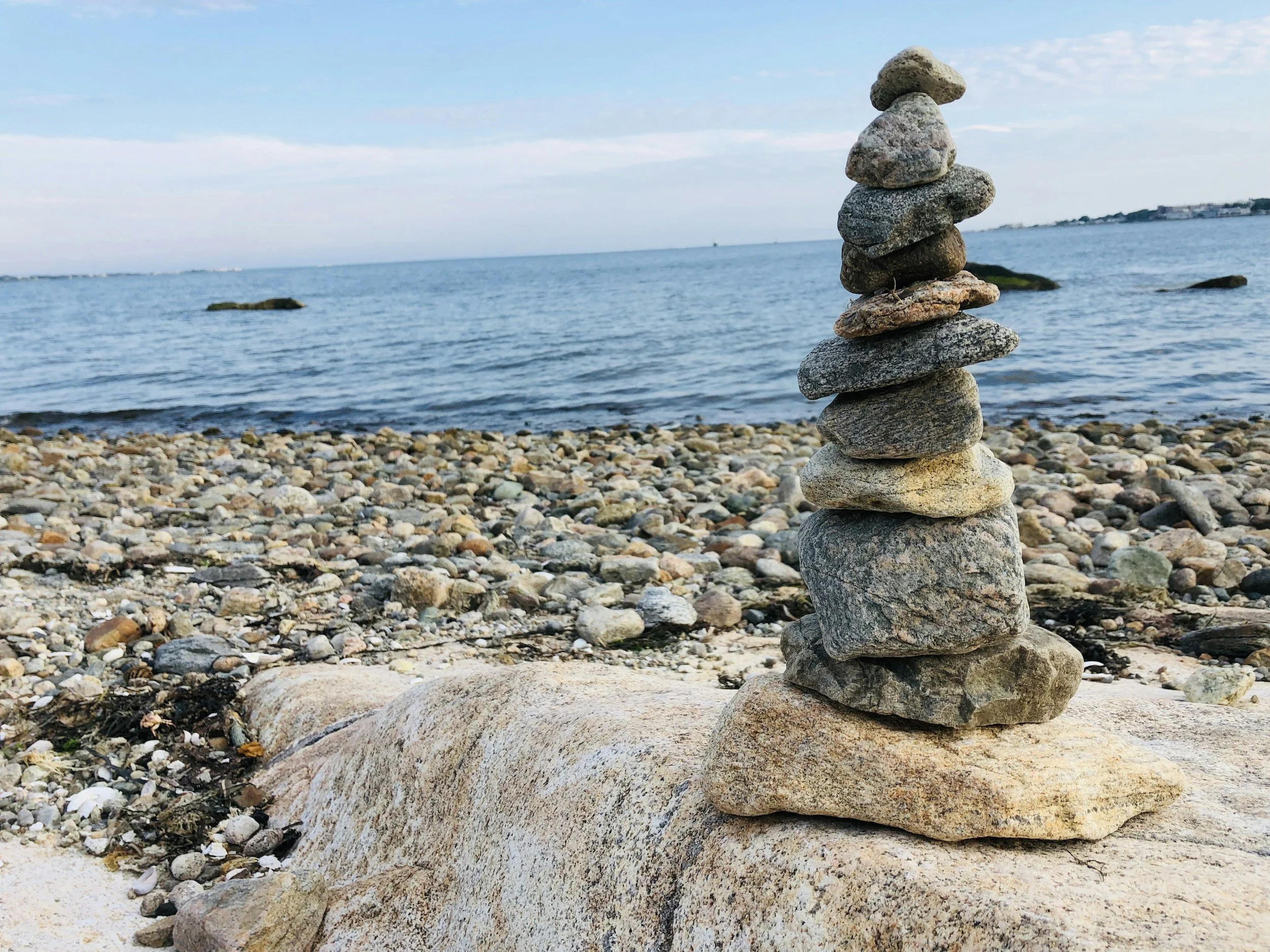 Stacked rocks on a beach with water and sky in the background