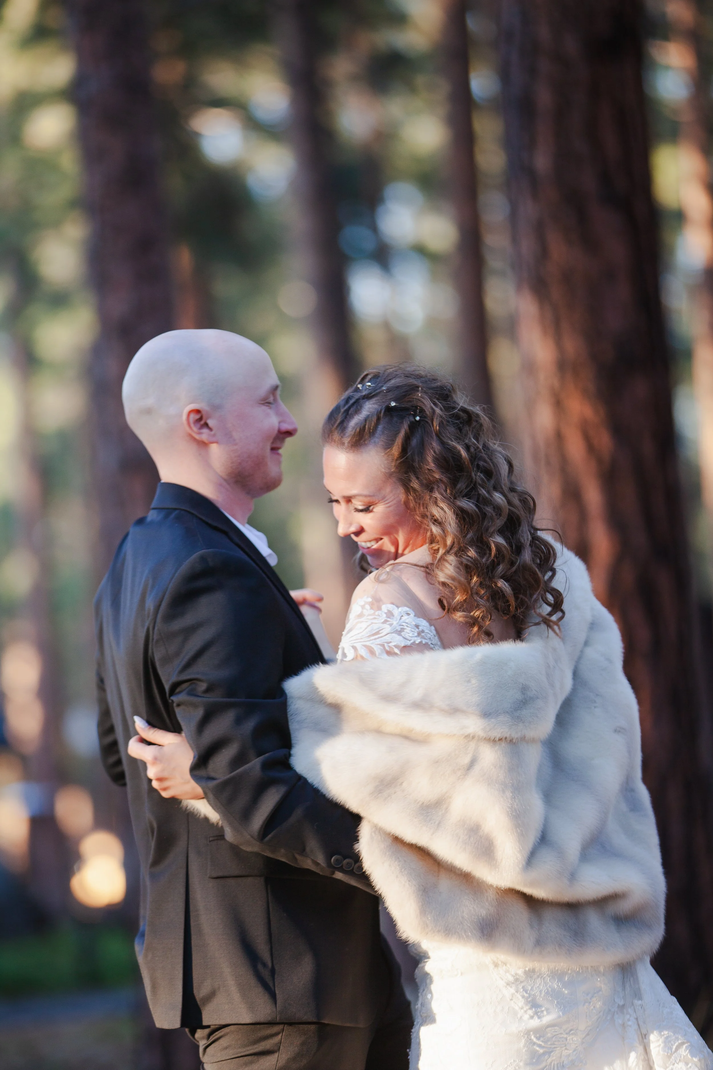 Bride and groom embracing beneath towering ponderosa pines. Five Pines Lodge. Sisters Oregon. 