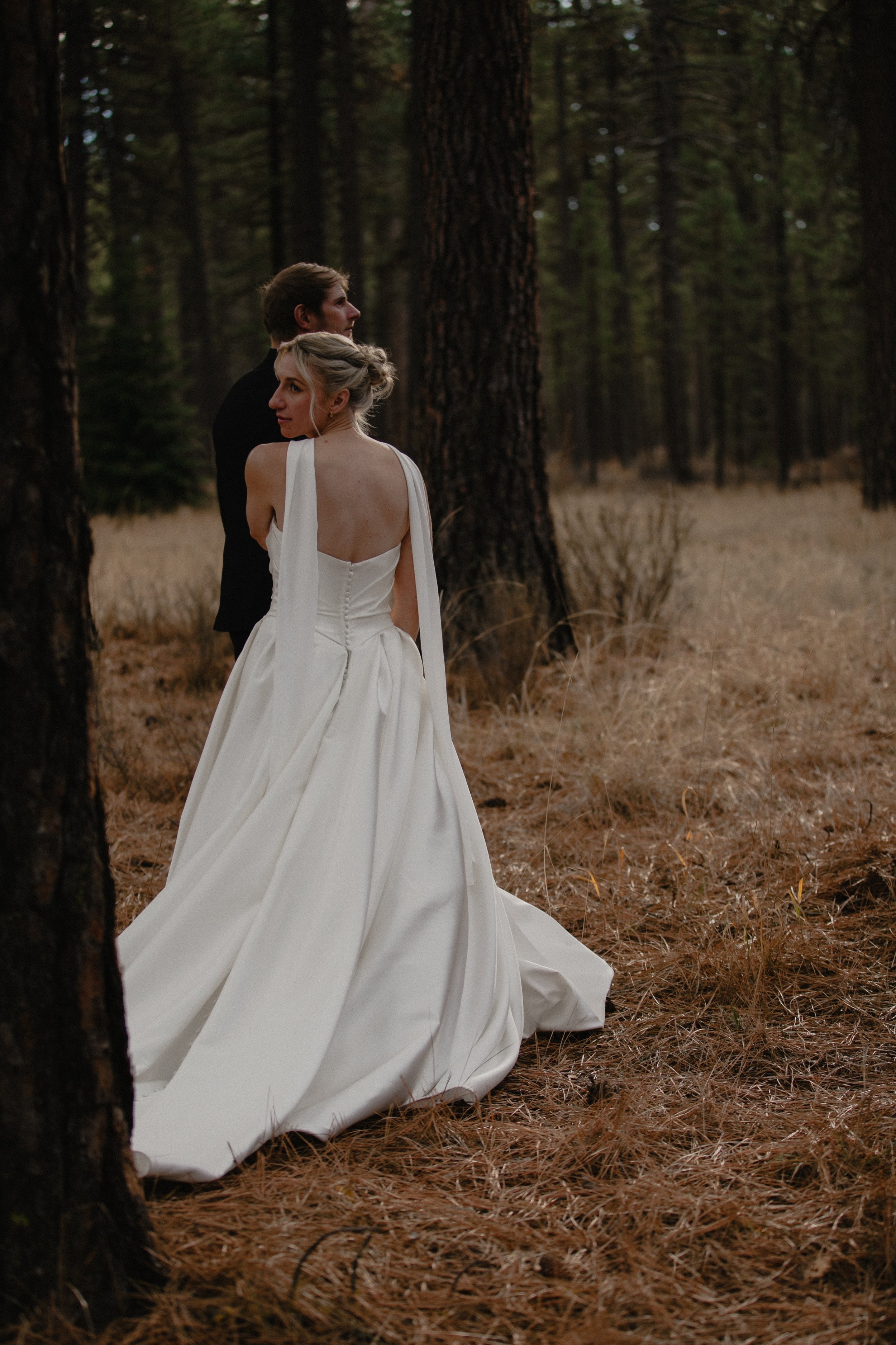 Bride walking through the pine forest in a sculptural white wedding gown near Camp Sherman, Oregon.