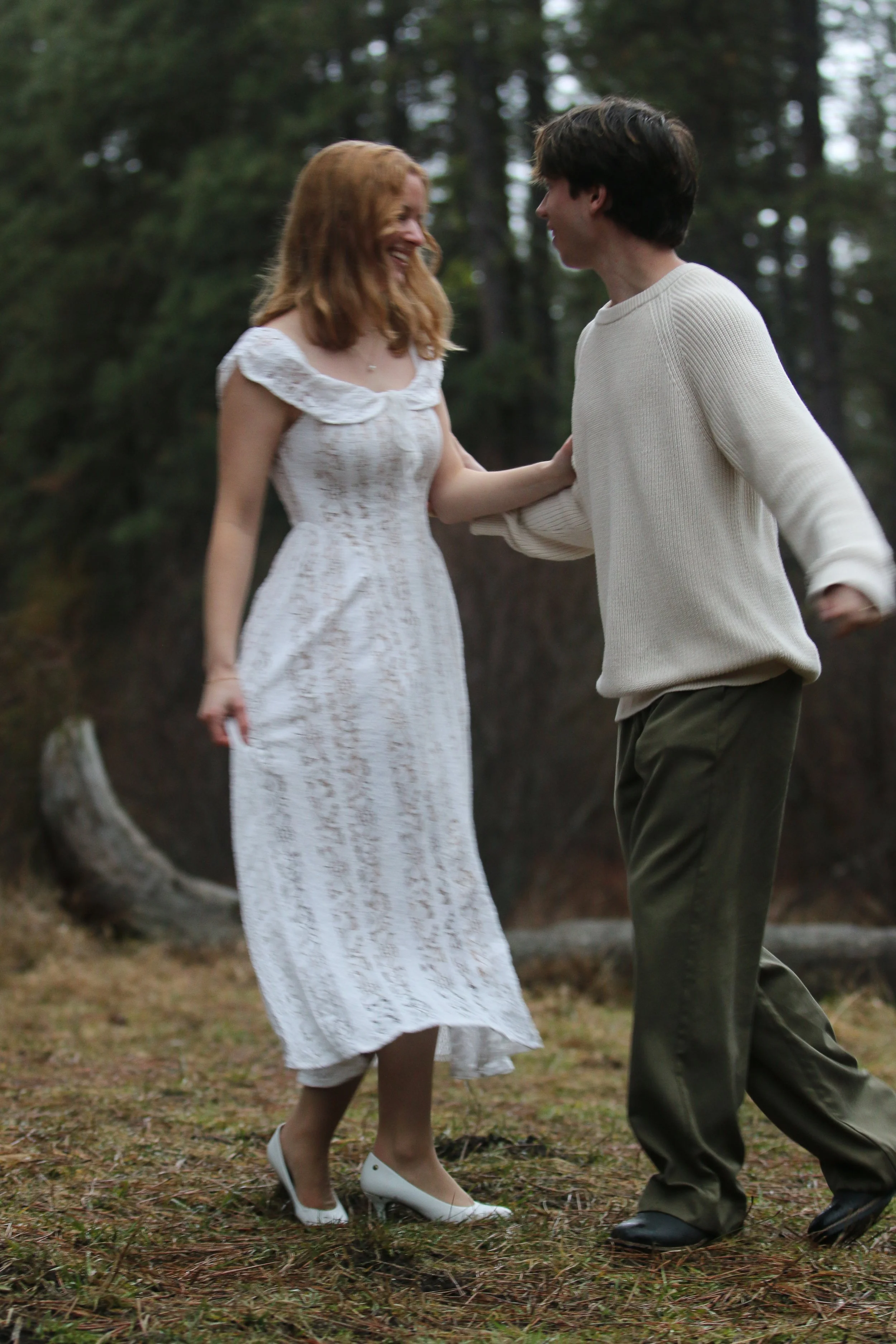 Bride and groom walking through the forest in neutral winter attire during their Camp Sherman engagement photos.