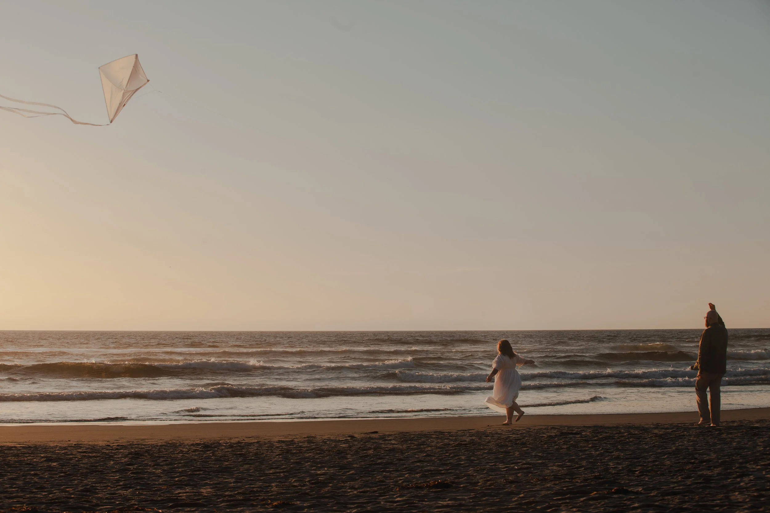 Oregon Coast engagement session at Hug Point with couple flying a kite at sunset