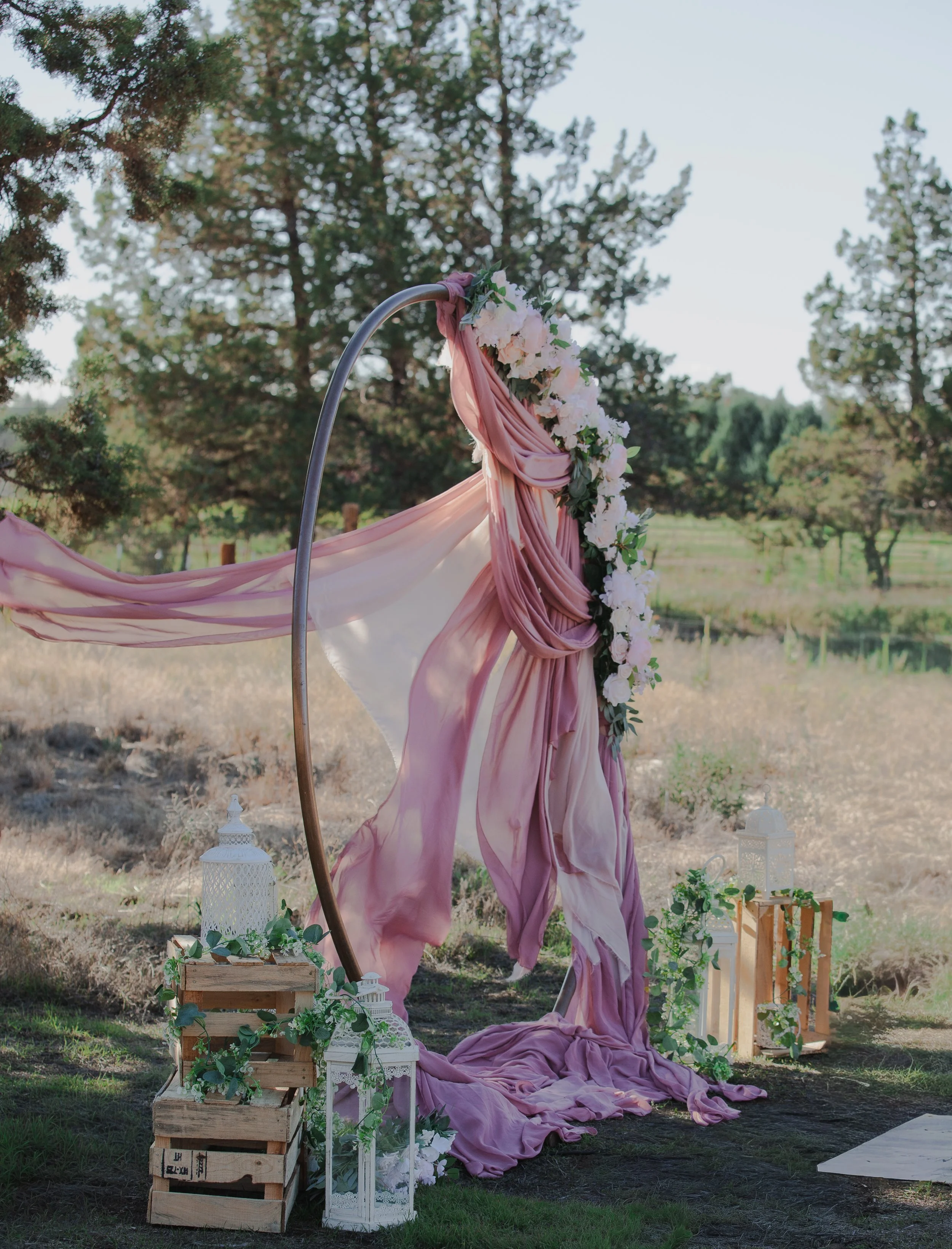  Handmade wedding ceremony arch draped in soft pink fabric on a private ranch in Central Oregon 
