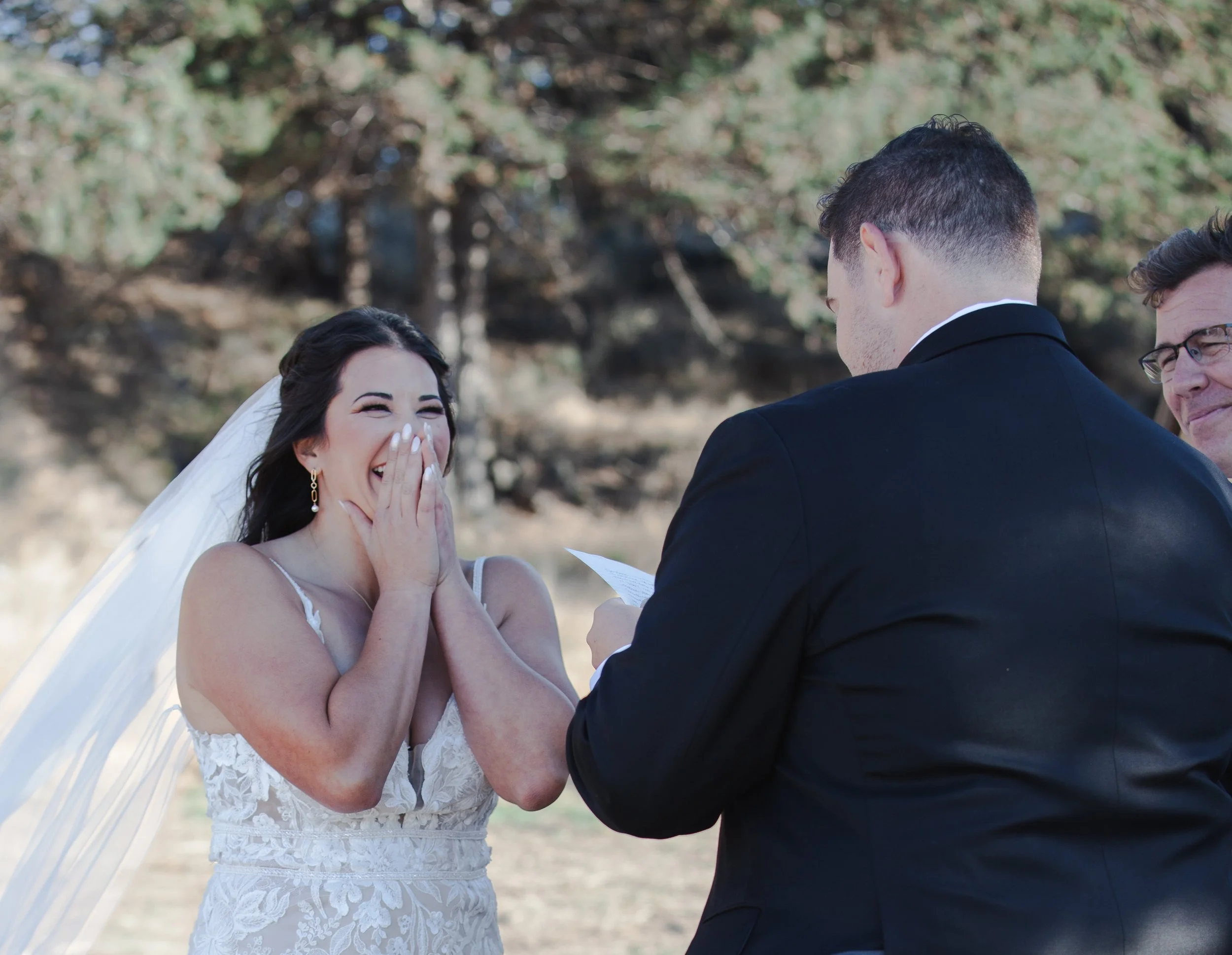  Bride and groom laughing while exchanging personal vows at their Central Oregon ranch wedding 