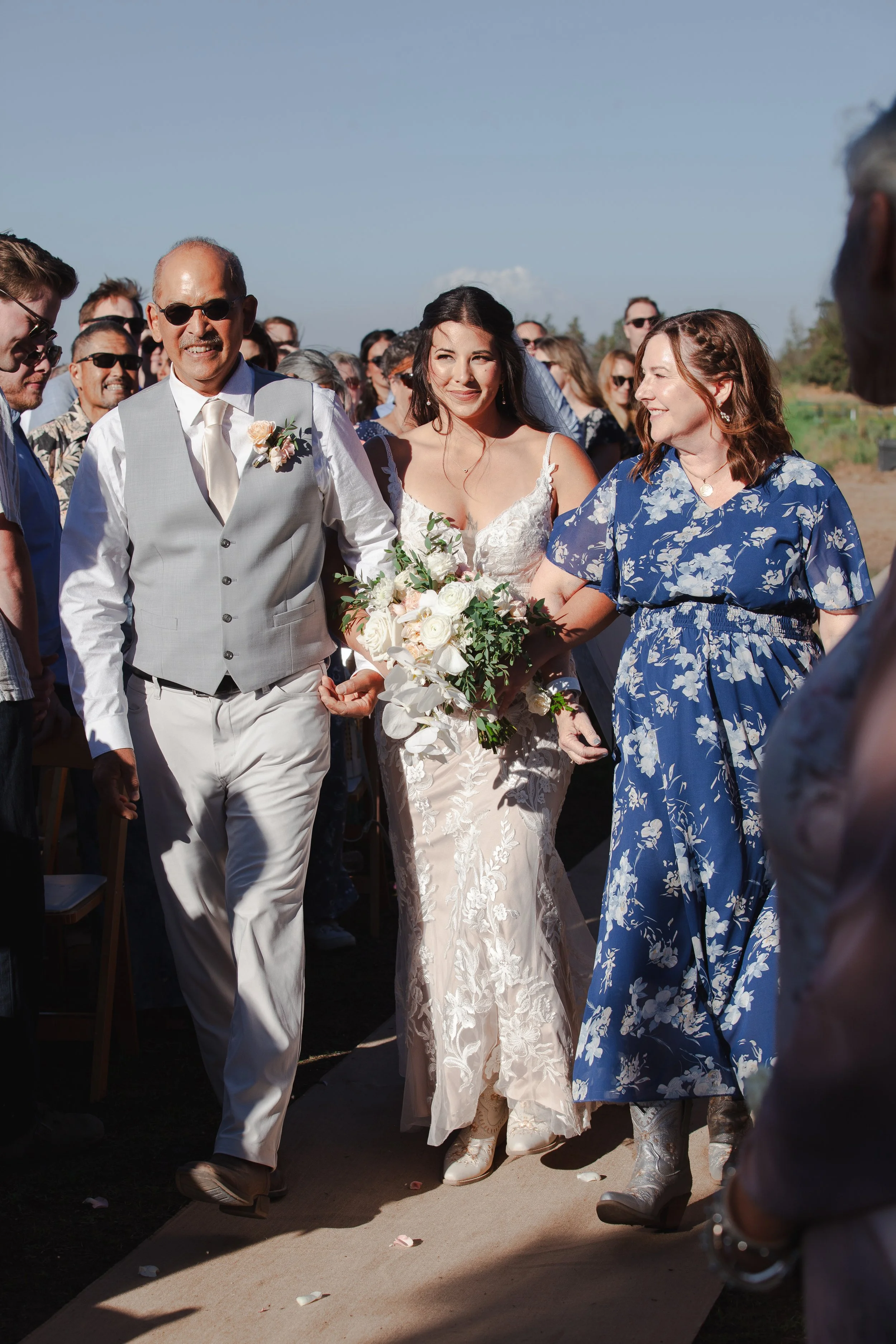  Bride walking down the aisle with both parents during her outdoor ranch wedding in Bend, Oregon 