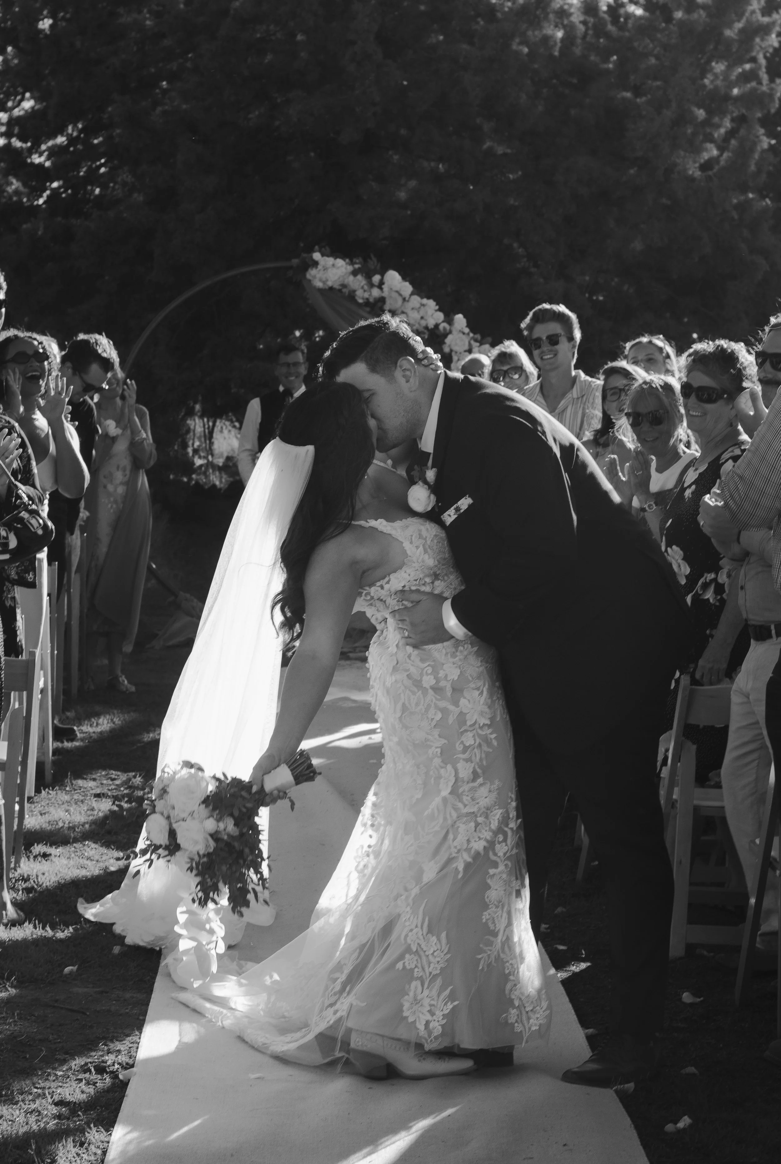  Black and white photograph of the newlyweds kissing after their outdoor ranch wedding ceremony in Bend, Oregon 