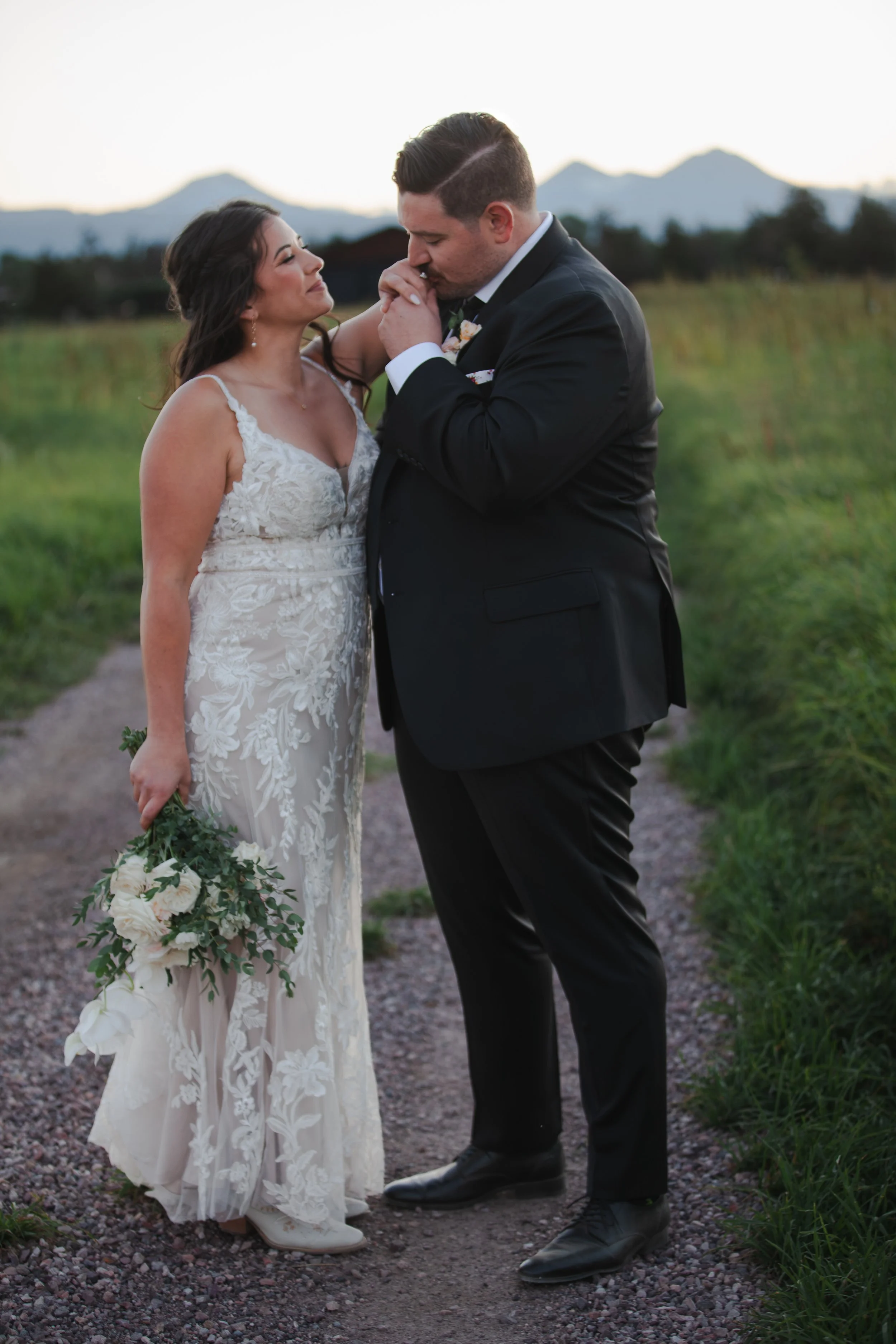  Newlyweds kissing beneath the Three Sisters mountains at sunset after their Bend, Oregon ranch wedding 