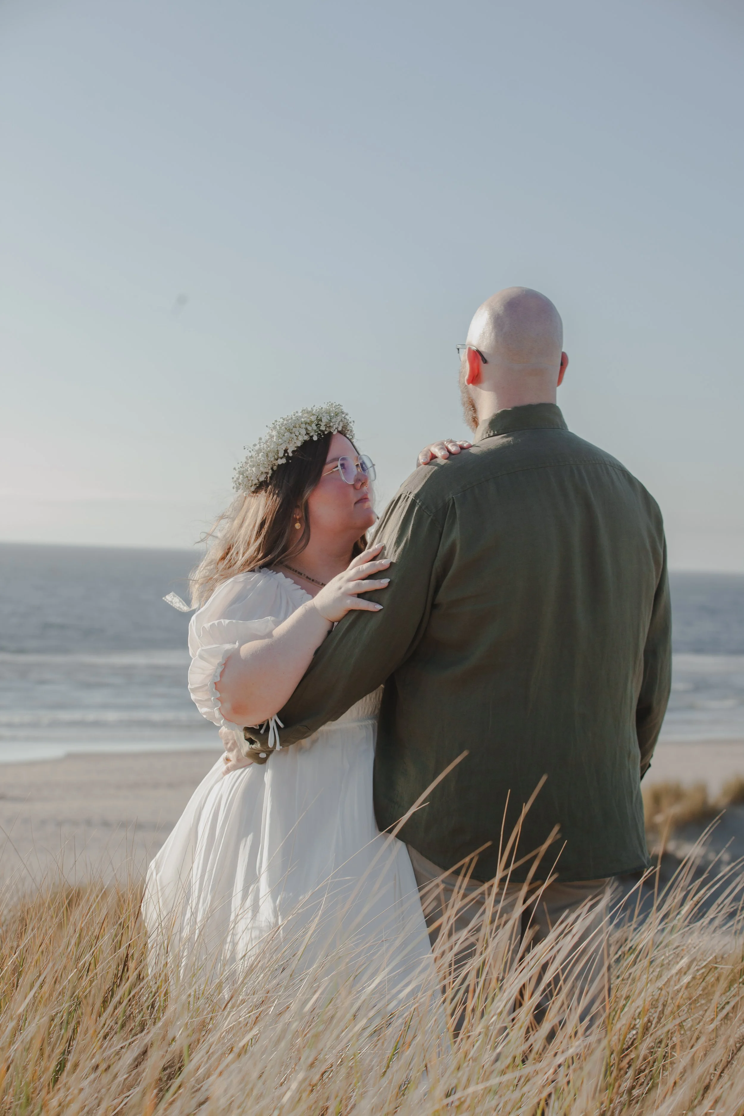 Windswept Oregon Coast engagement photo with couple overlooking the Pacific Ocean
