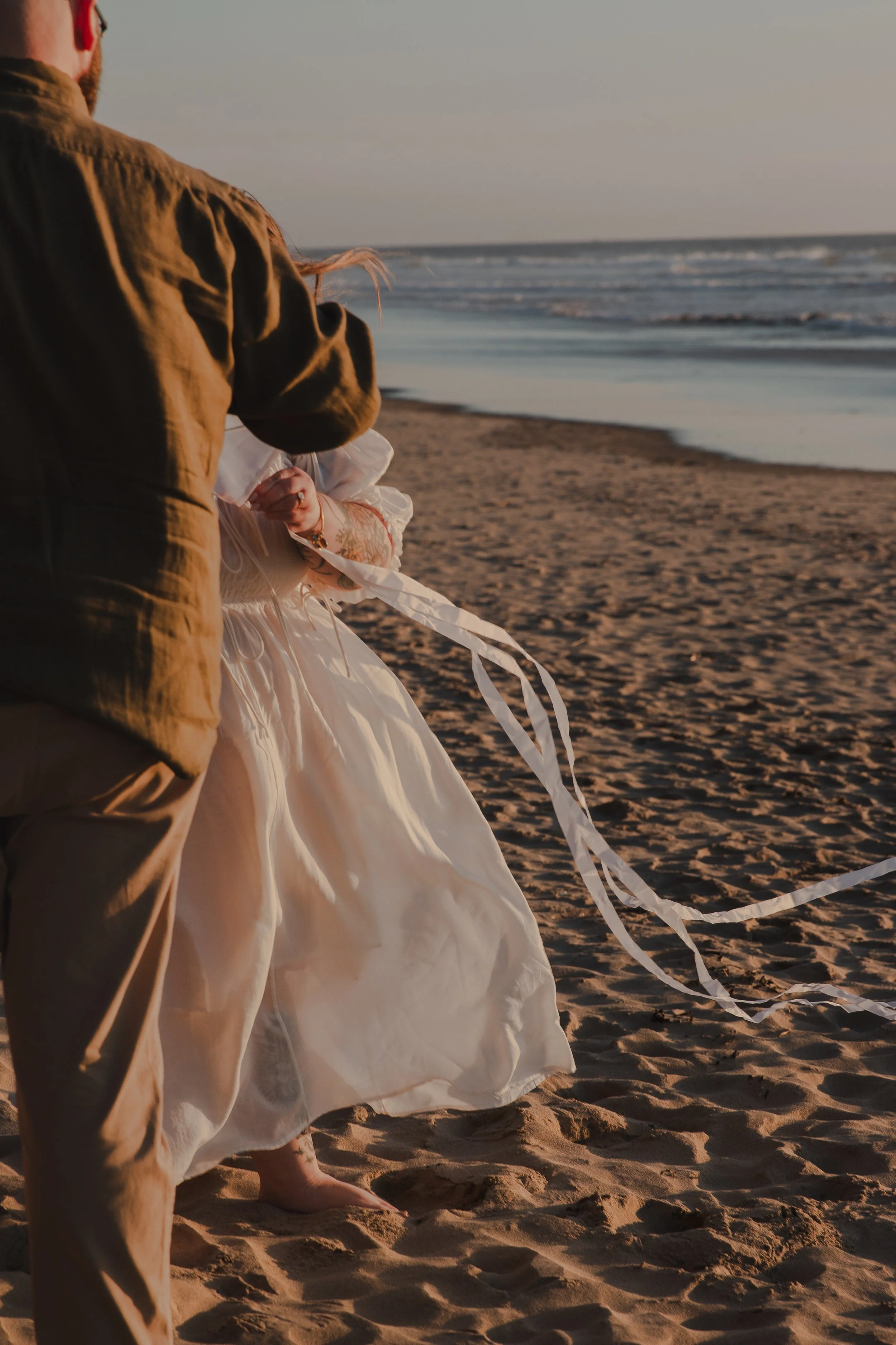 Cinematic beach engagement photo with couple and kite at sunset