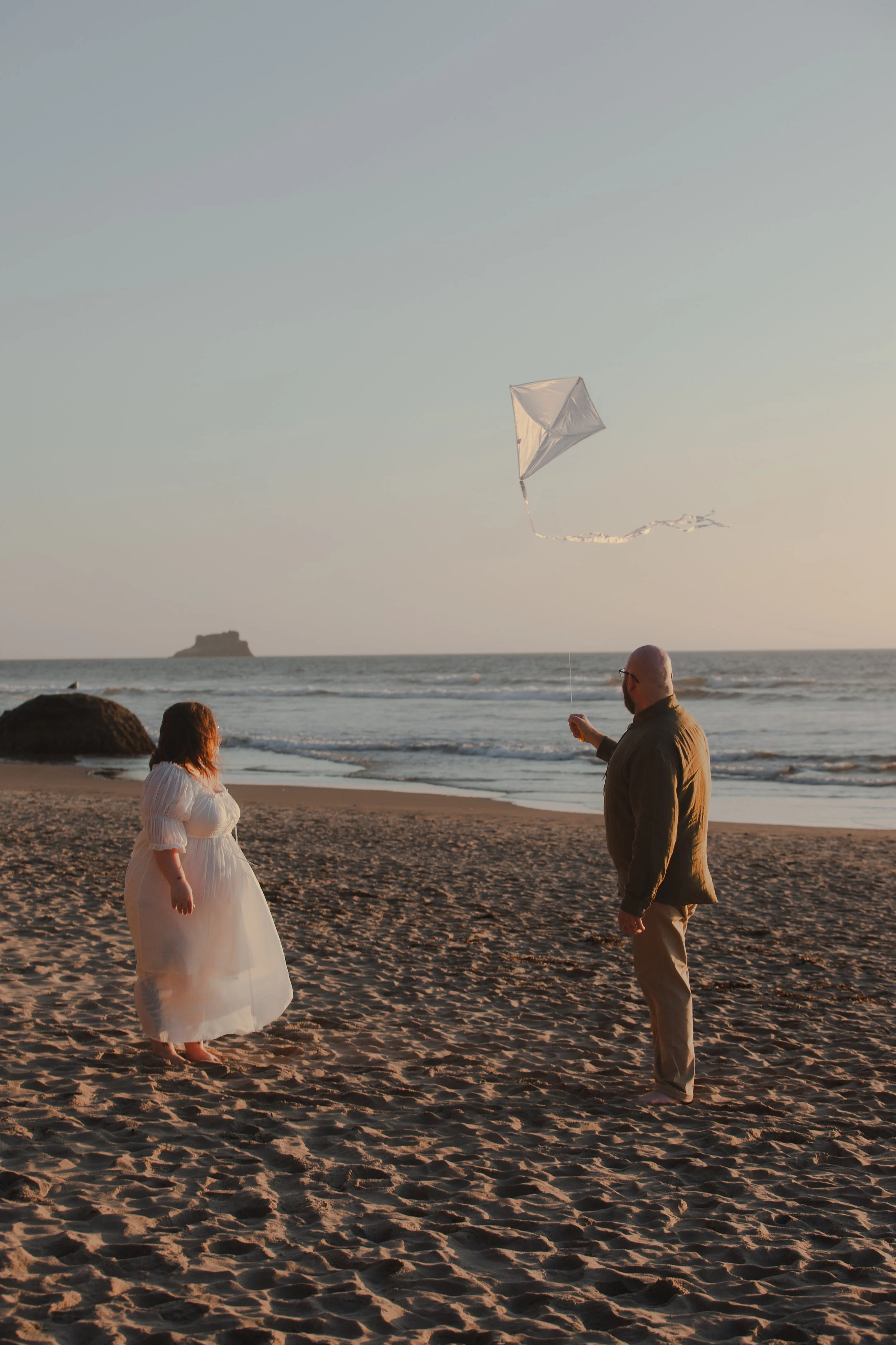 Couple flying a kite during sunset engagement session on the Oregon Coast