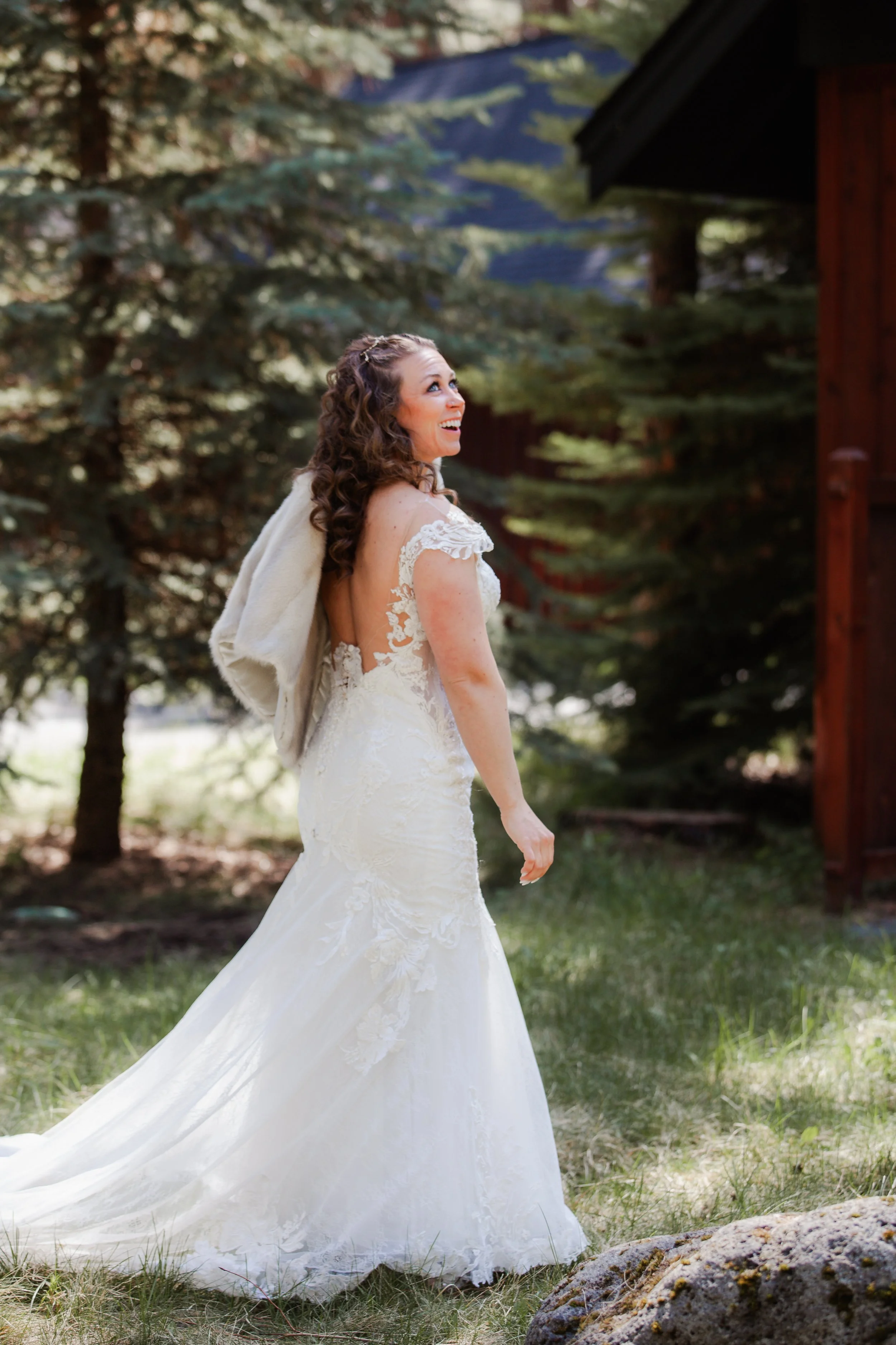 Bride walking through the forest in her lace wedding gown at FivePine Lodge in Sisters, Oregon.