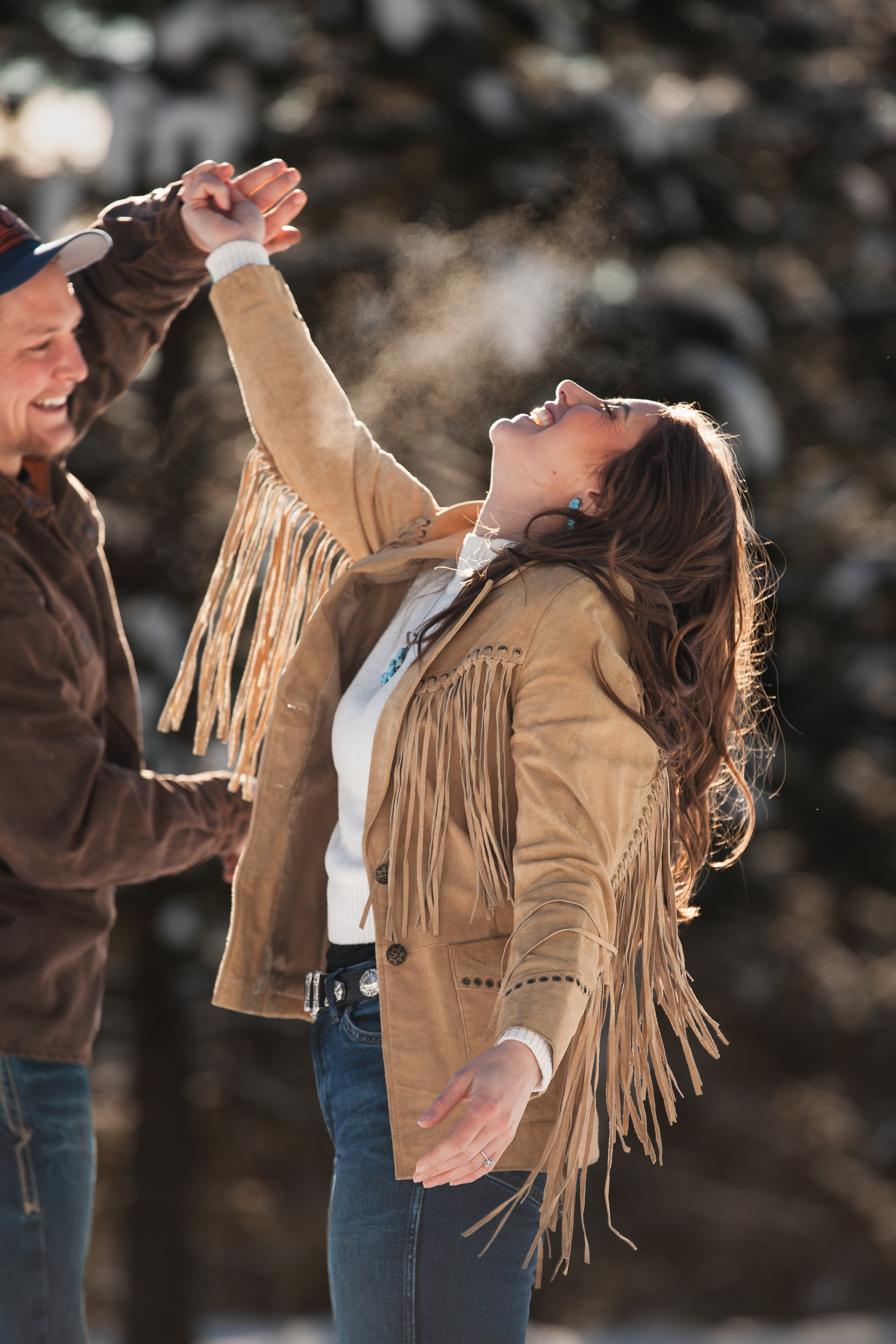 Engaged couple laughing together in warm winter sunlight during their McCall, Idaho engagement photos.