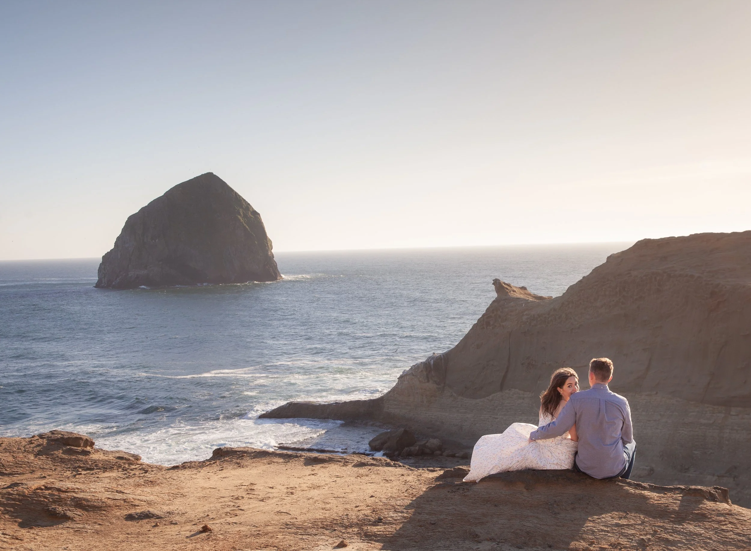 Candid engagement portrait overlooking the rocky coastline near Cape Kiwanda in Pacific City.