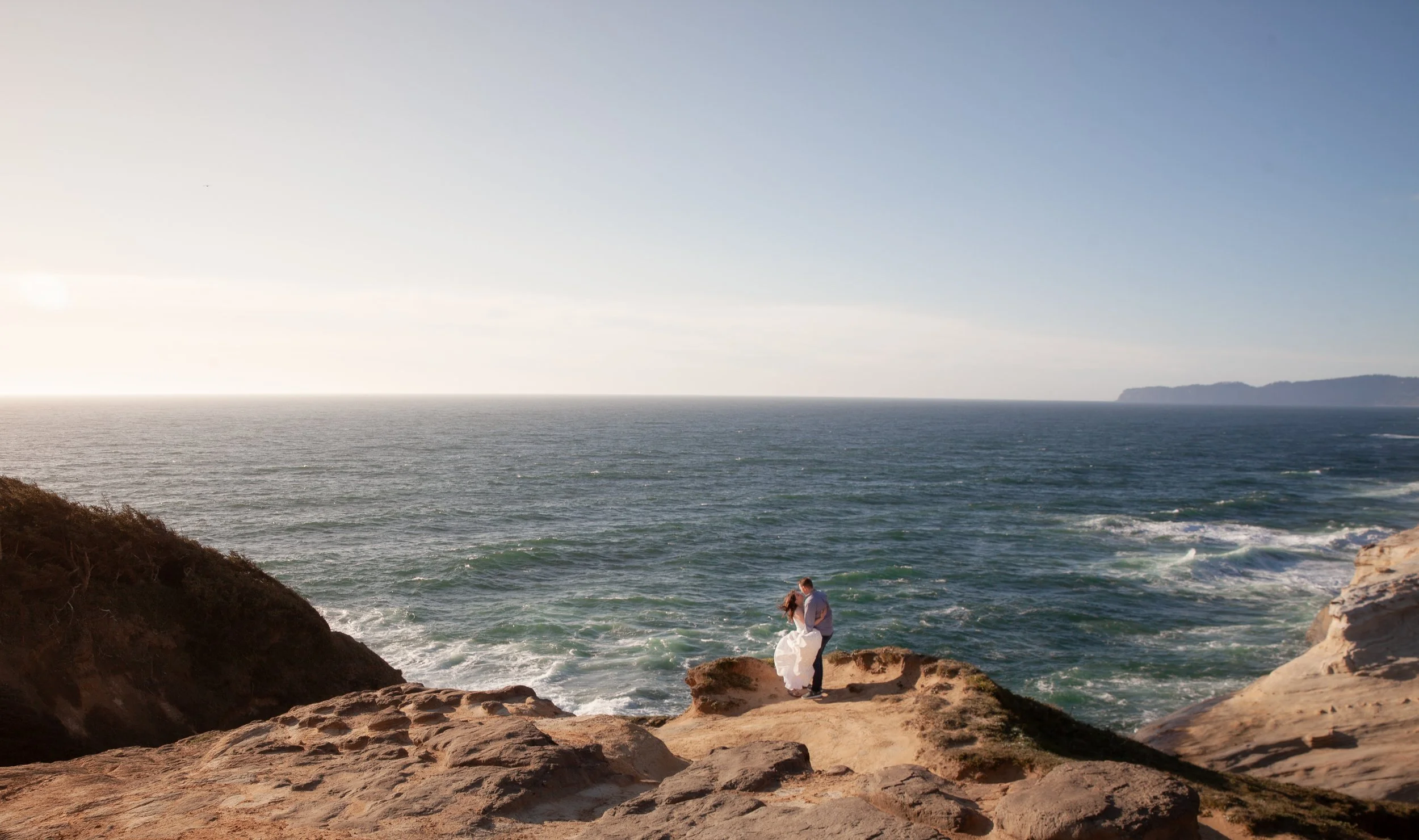 Wide coastal engagement portrait overlooking the Pacific Ocean near Pacific City, Oregon.