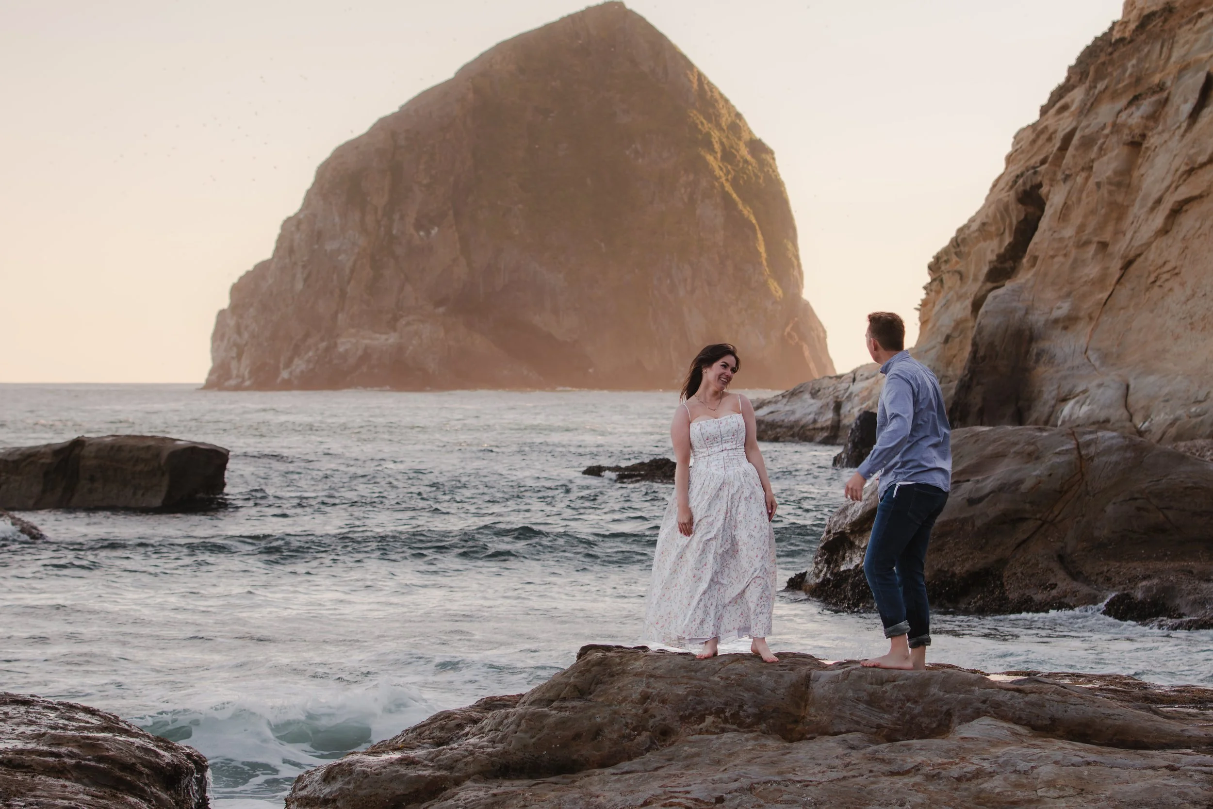 Engaged couple walking along the rocky coastline near Cape Kiwanda on the Oregon Coast.