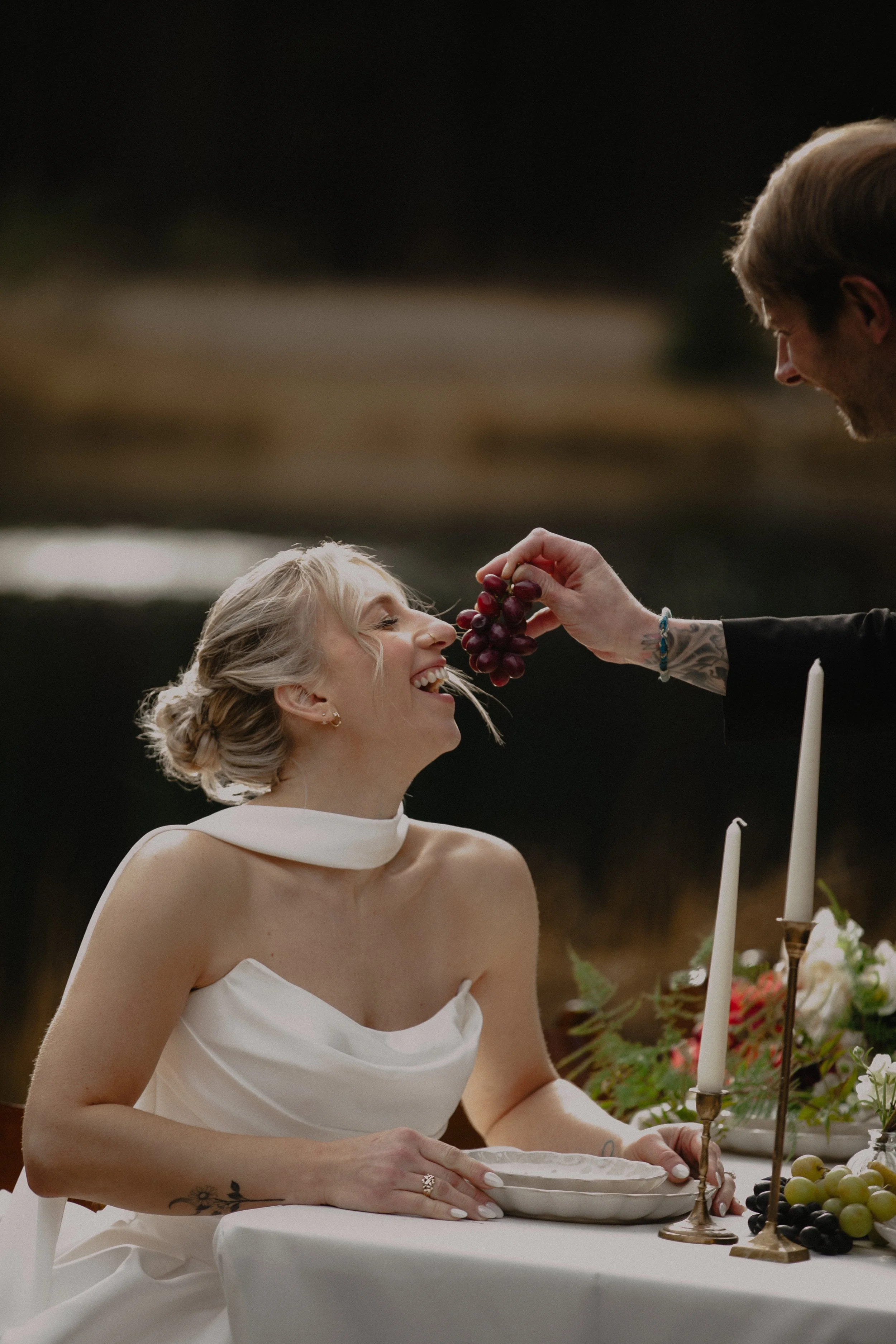 Bride seated at an intimate candlelit wedding table beside a forest lake in Central Oregon.