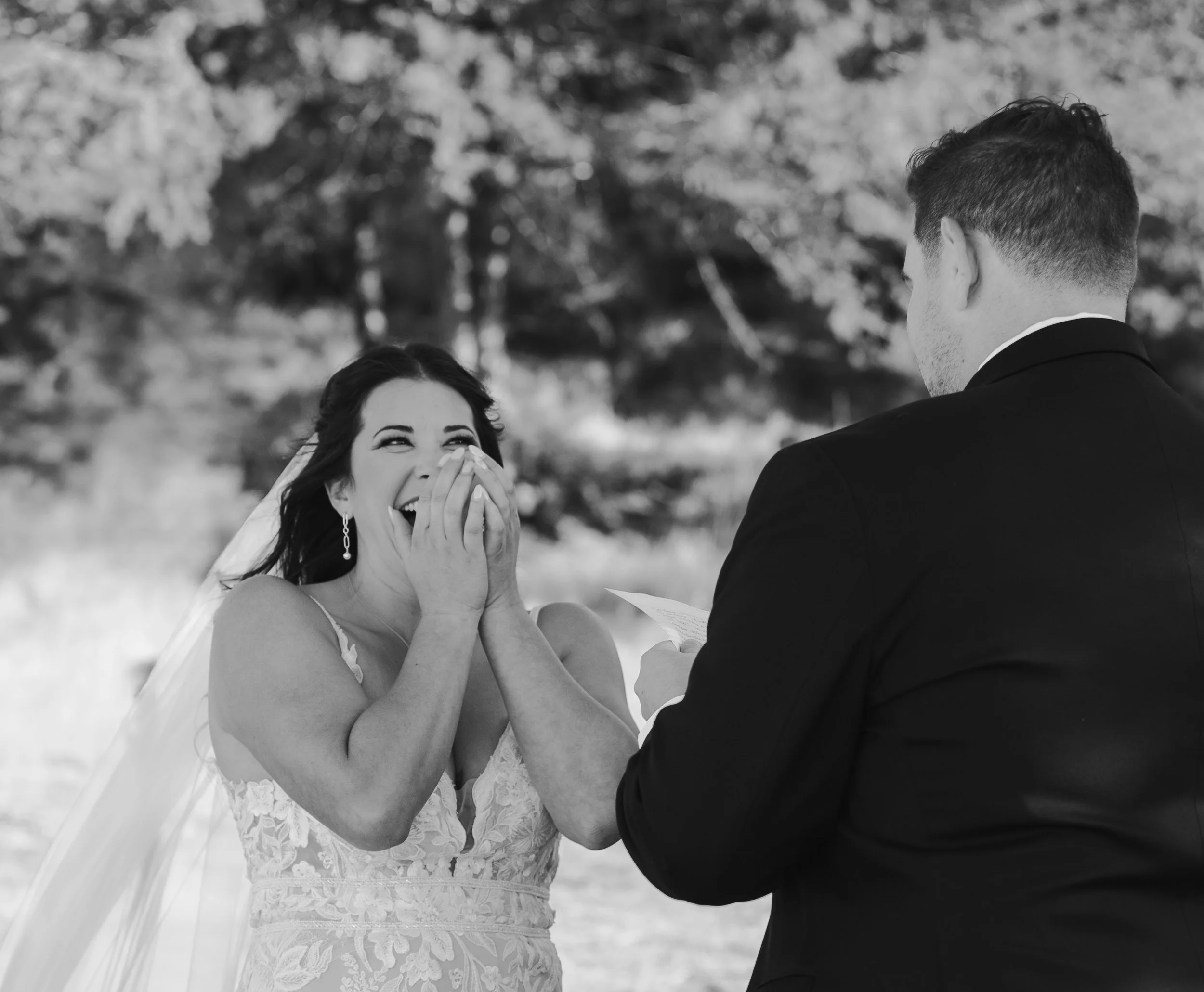 Black and white photograph of the bride laughing during her outdoor wedding ceremony.