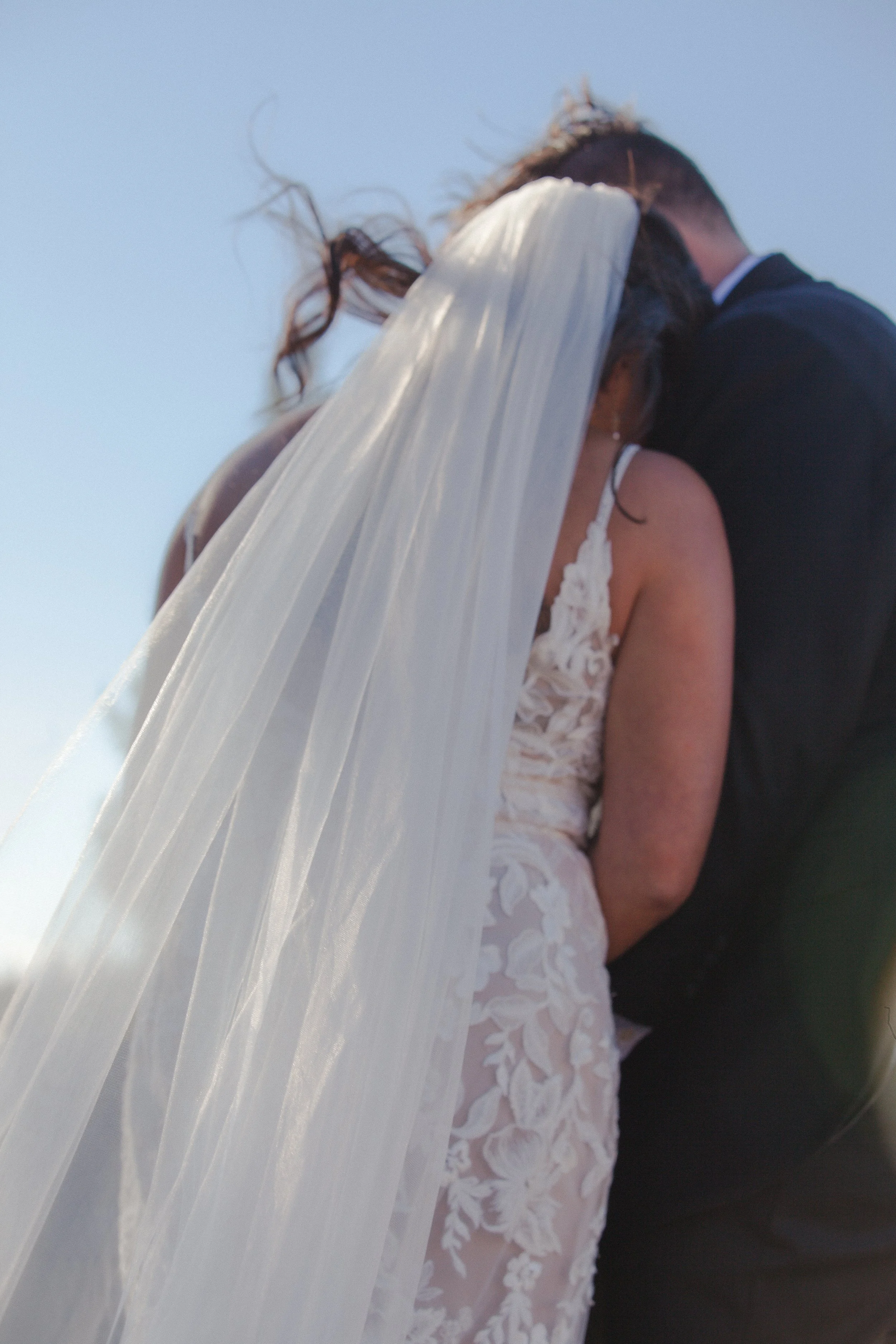 Close-up of the bride and groom beneath her flowing wedding veil in the High Desert sunlight.