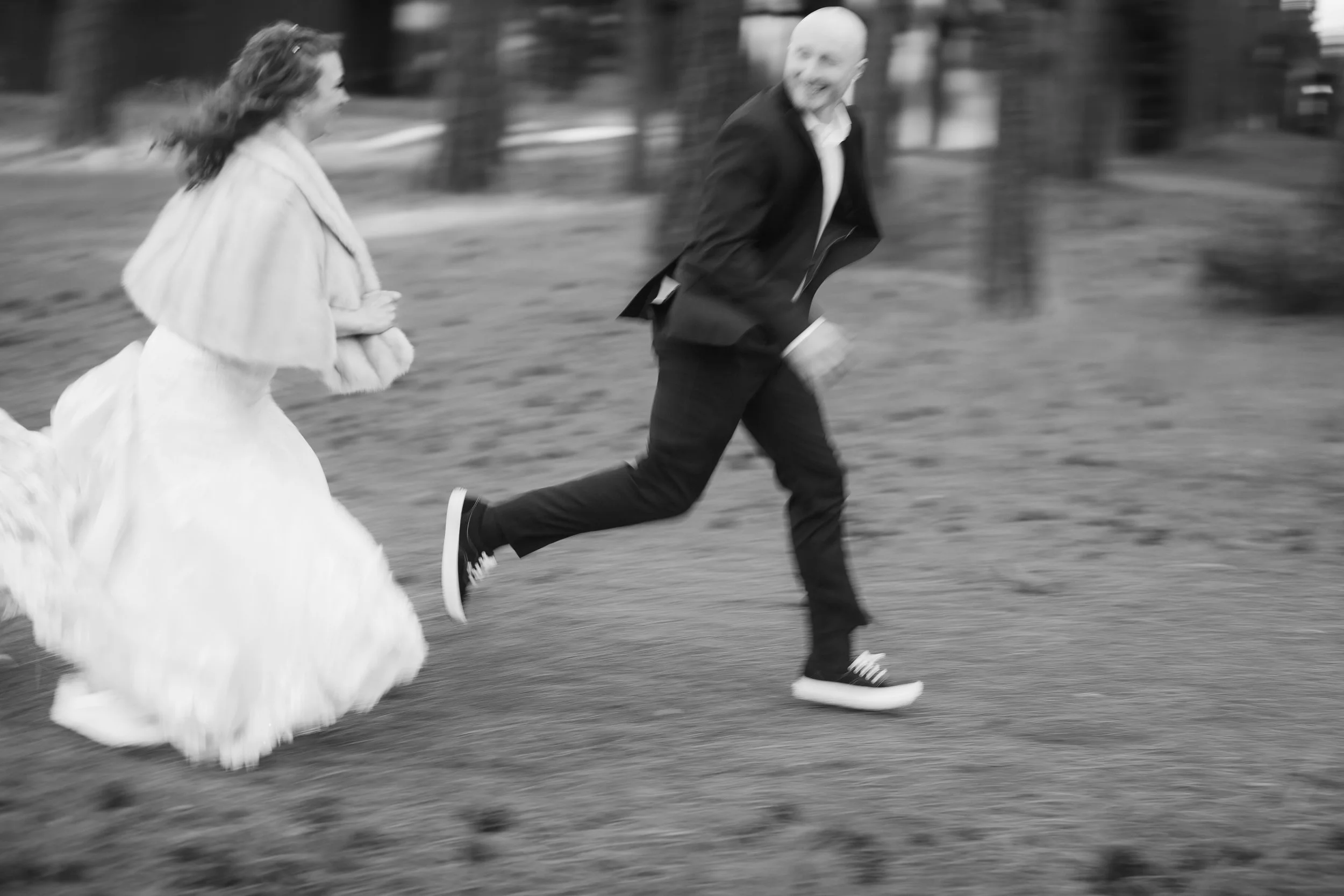 Bride and groom running through the pine forest in a black-and-white wedding photograph in Sisters, Oregon.