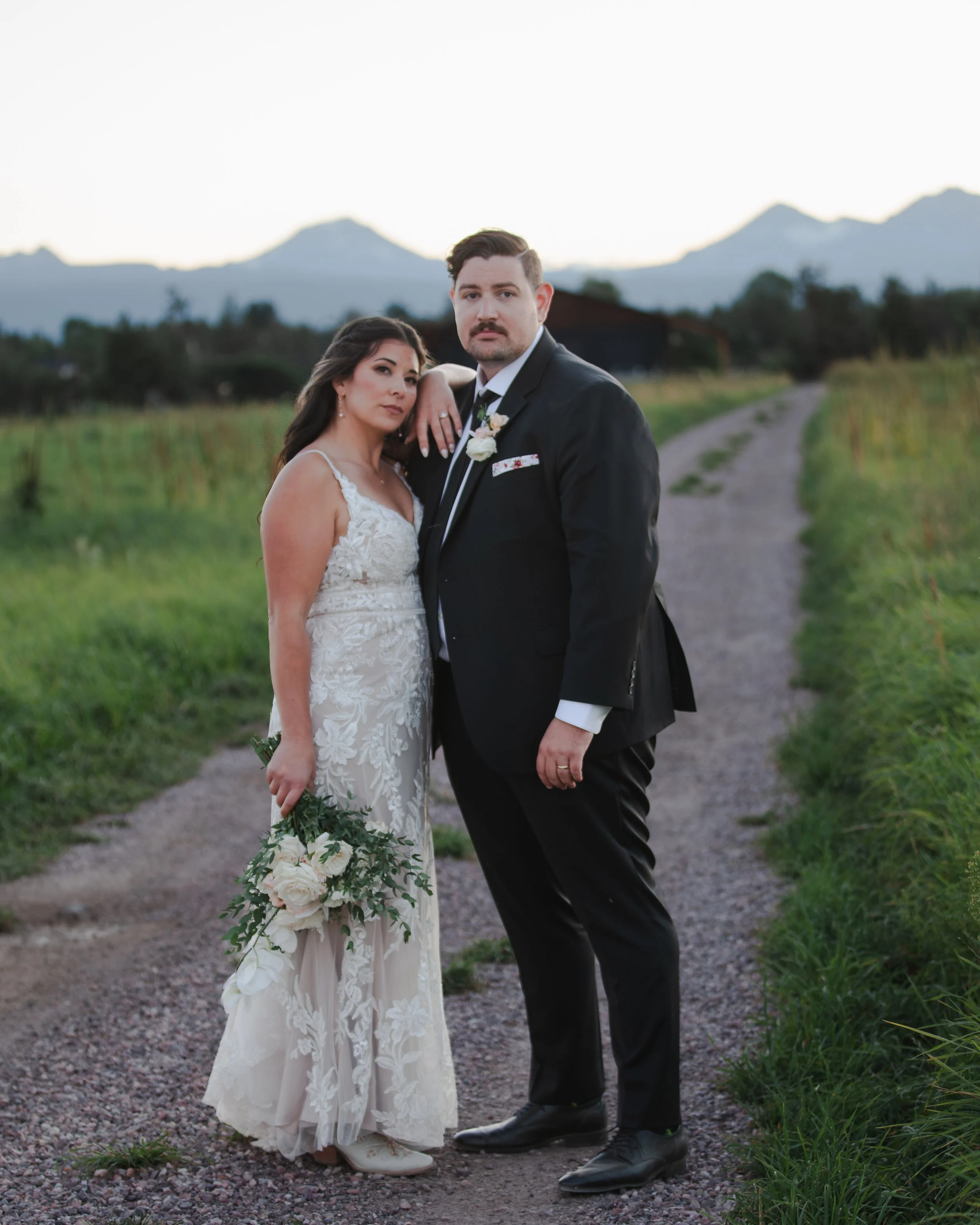 Newlyweds standing on a ranch road with the Three Sisters mountains behind them near Bend, Oregon.