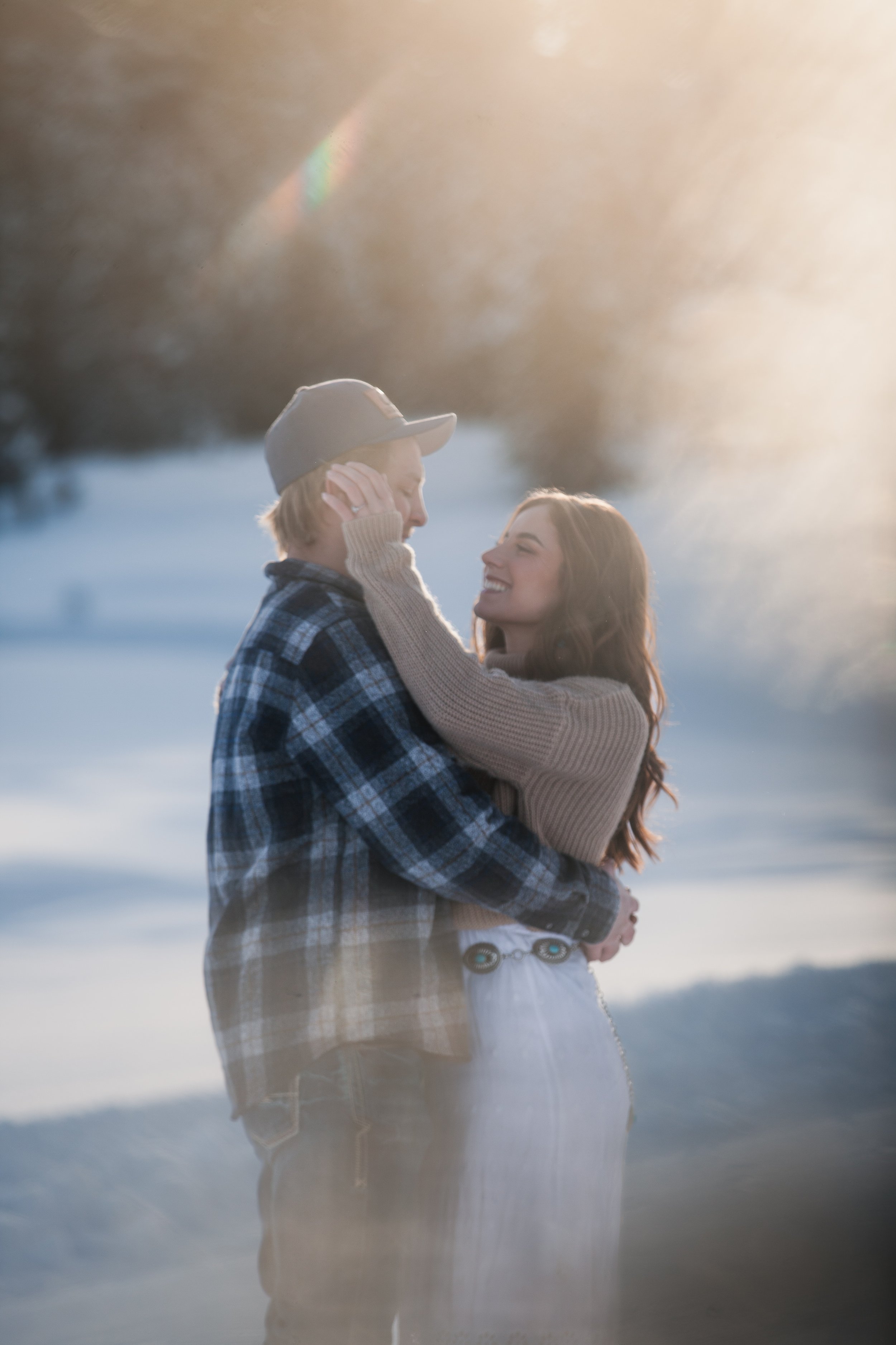 Bride and groom embracing in golden winter light among the snowy pines of Payette National Forest.