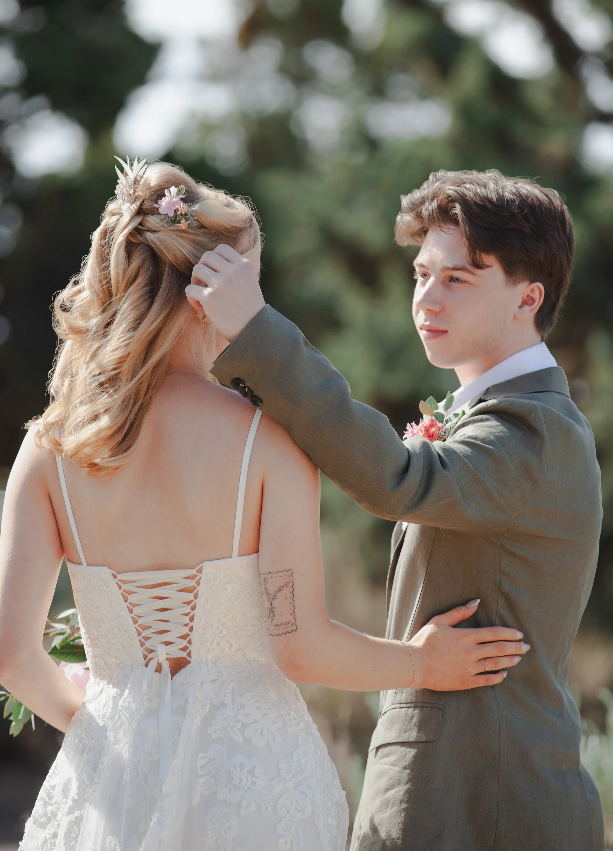 Groom gently fixing his bride's hair during an outdoor wedding portrait in Bend, Oregon