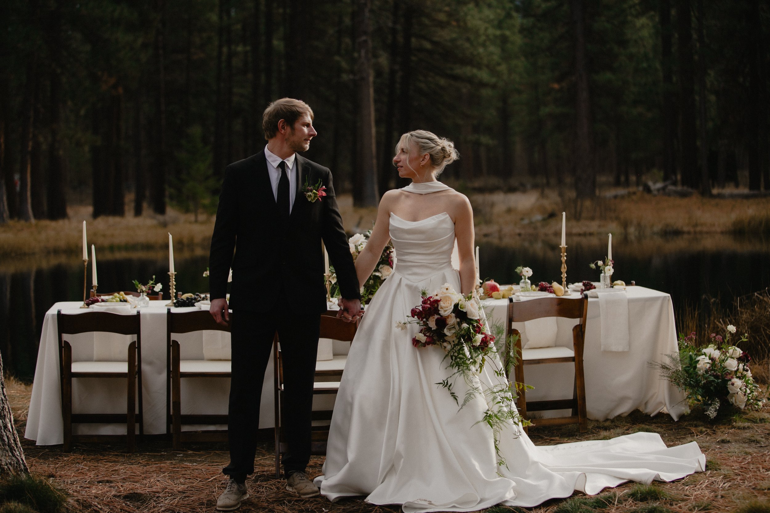 Editorial wedding portrait of a bride and groom beside a forest lake in Camp Sherman, Oregon.