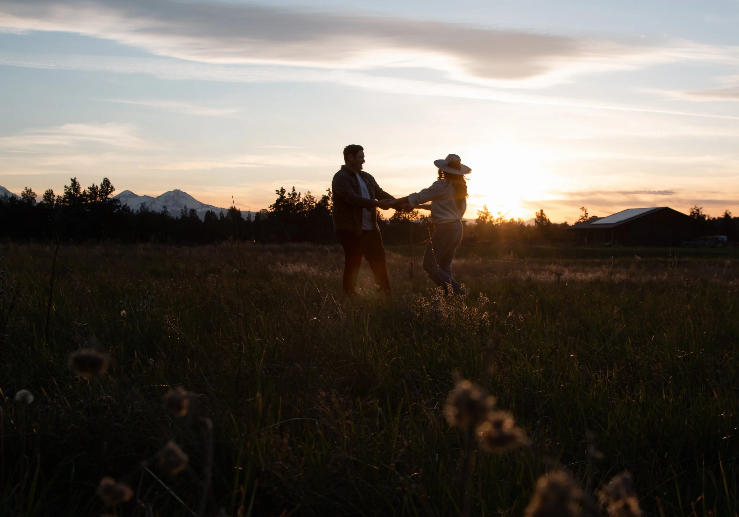 Engaged couple walking through a private ranch in Central Oregon during a golden-hour engagement session near Bend.