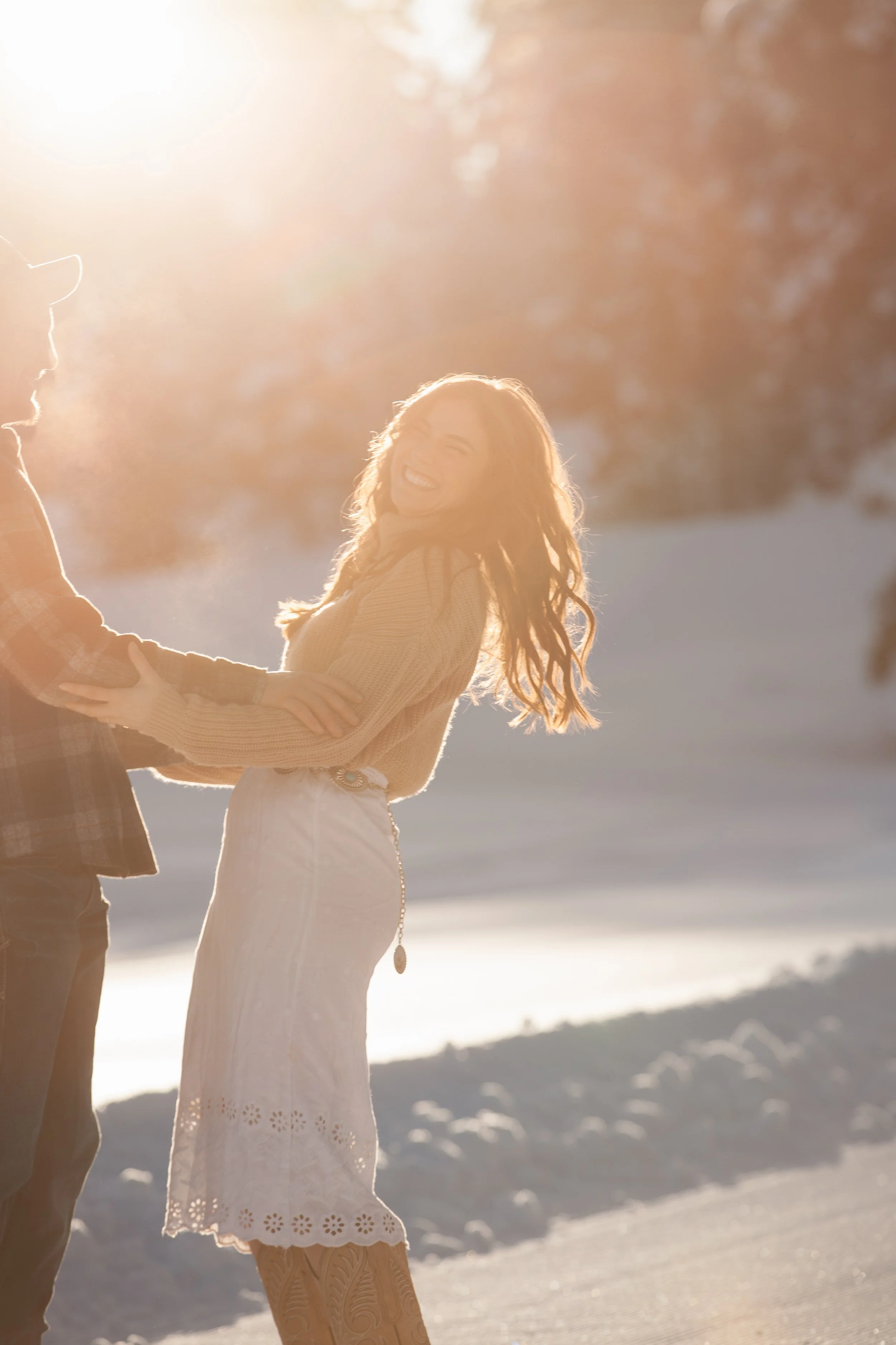 Bride-to-be smiling in a snowy pine forest during a winter engagement session near McCall, Idaho.