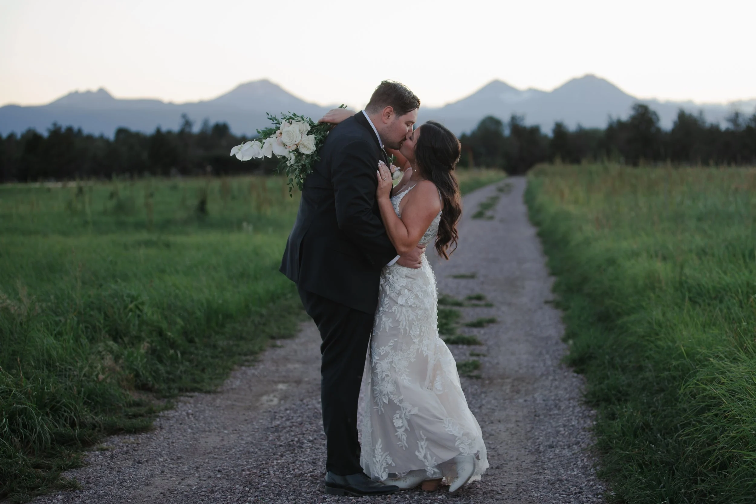 Newlyweds kissing beneath the Three Sisters mountains at sunset after their Bend, Oregon ranch wedding