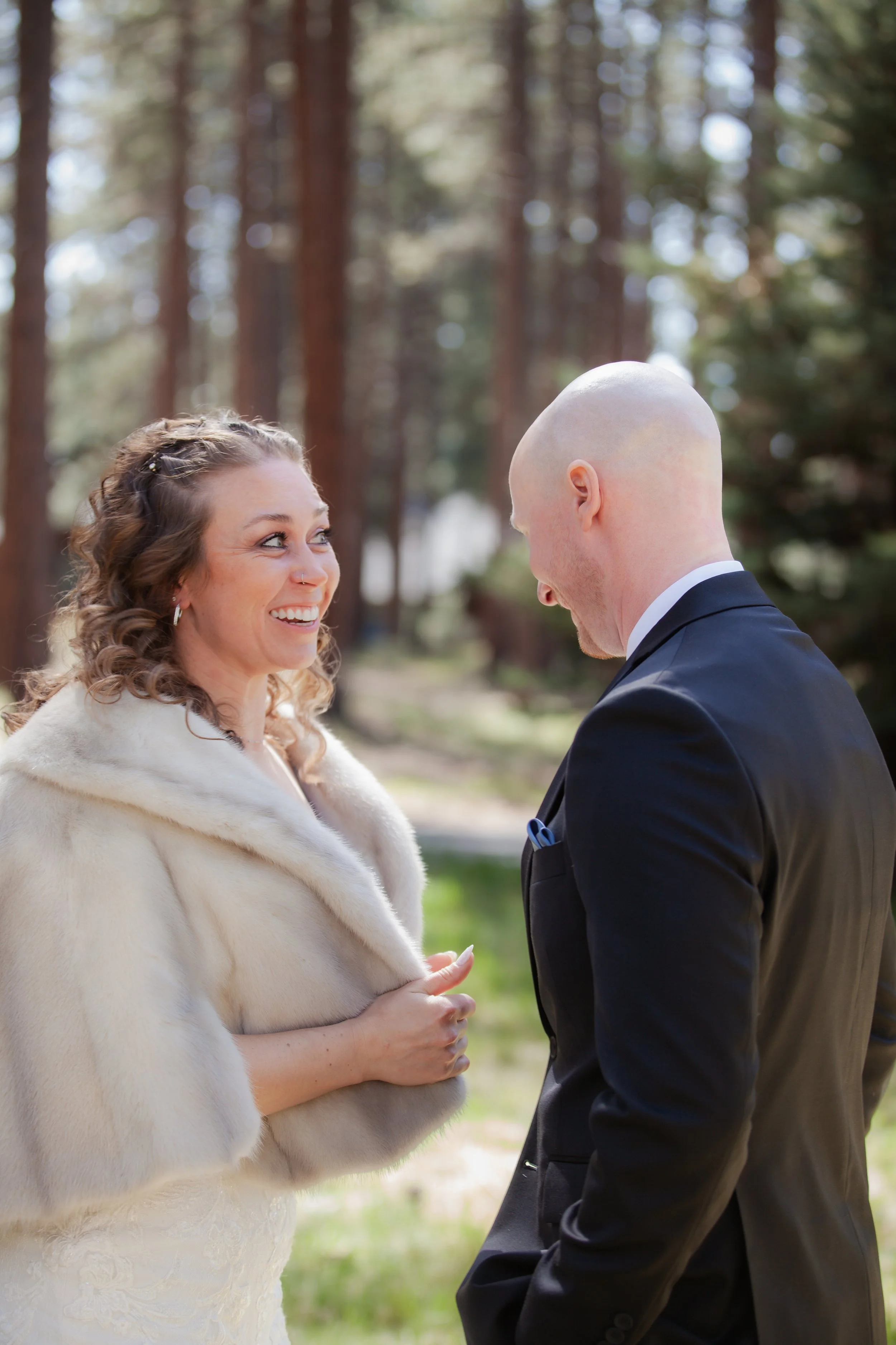 Bride and groom sharing a candid moment beneath the pines during their Sisters, Oregon wedding.