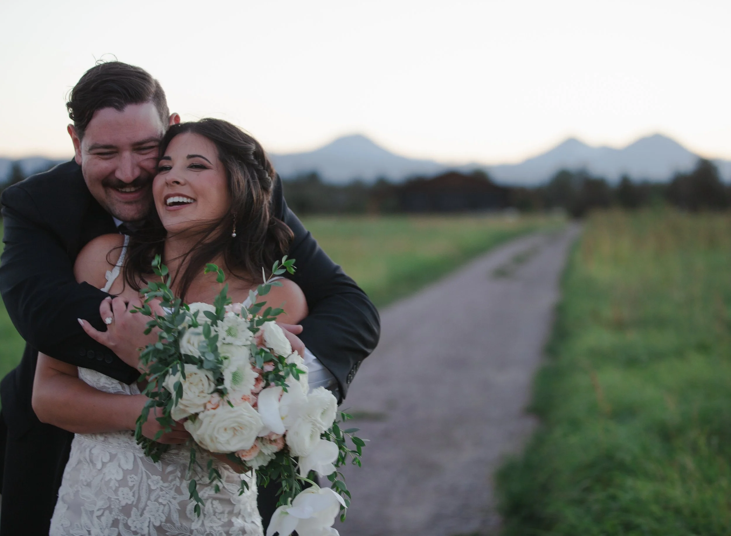 Bride holding her cascading bouquet with the Three Sisters mountains behind her near Bend, Oregon.
