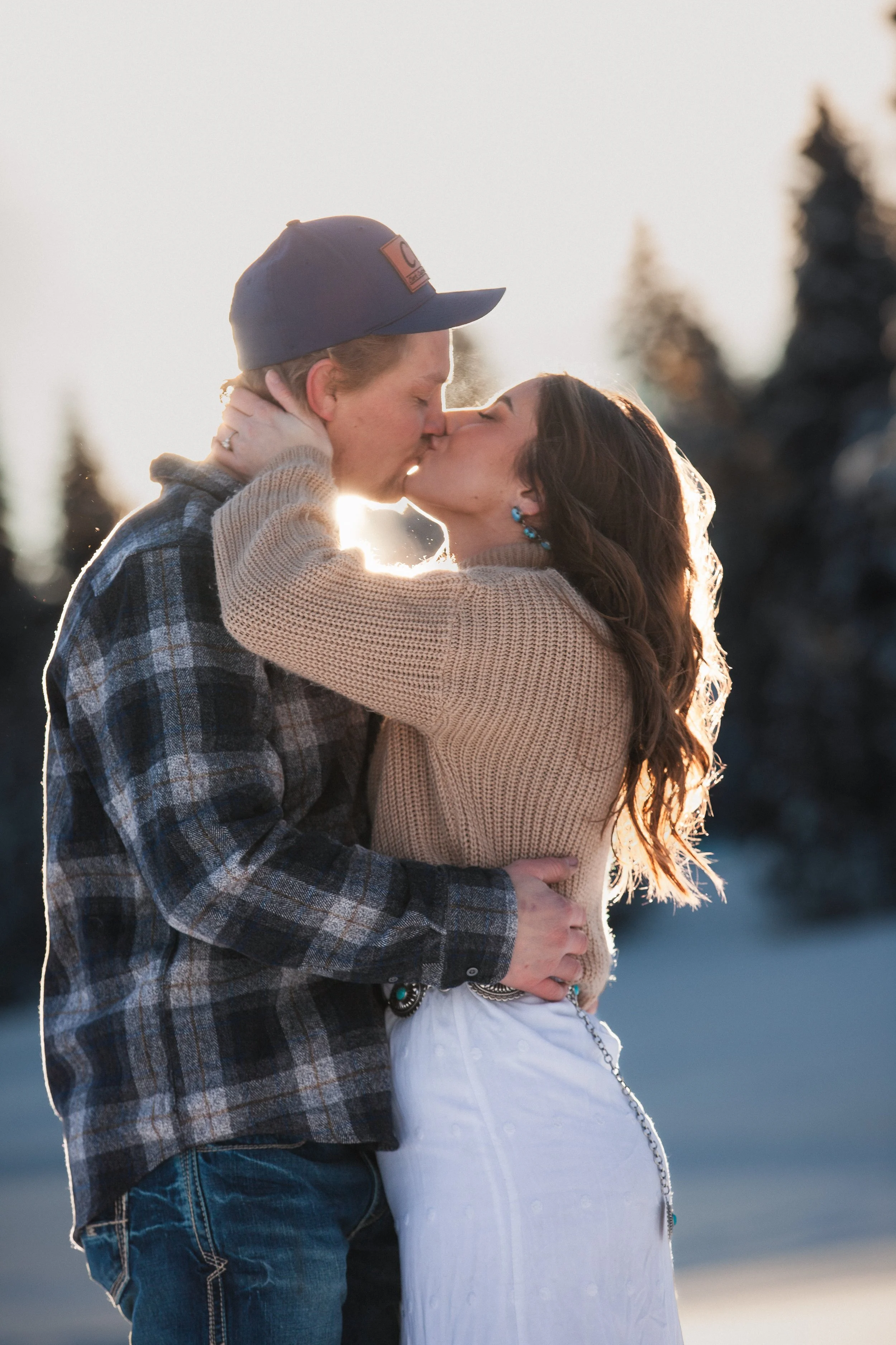 Bride and groom kissing beneath snow-covered pine trees in Payette National Forest, Idaho.
