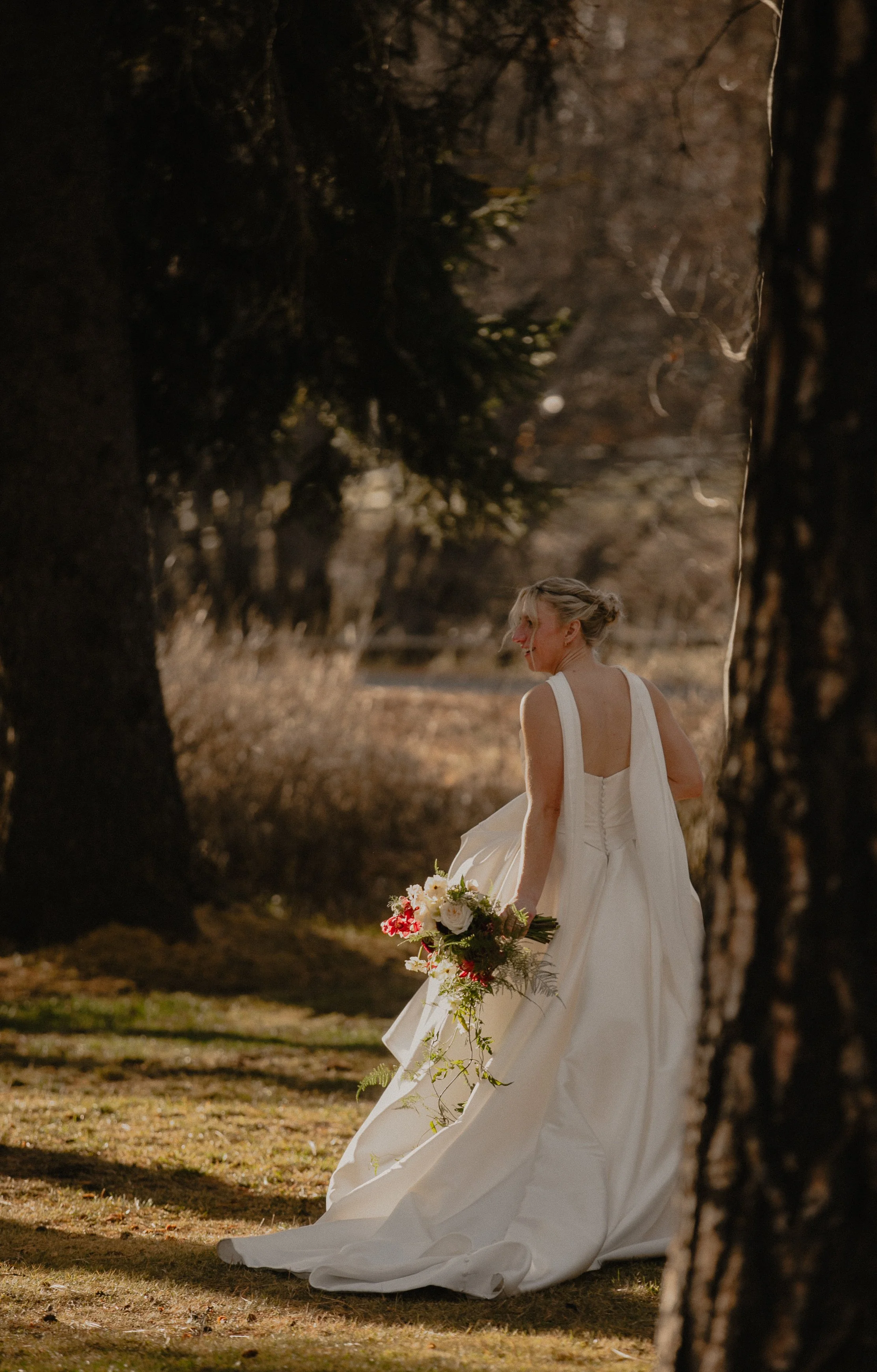 Editorial portrait of a bride in a white wedding gown surrounded by the forest near Sisters, Oregon.