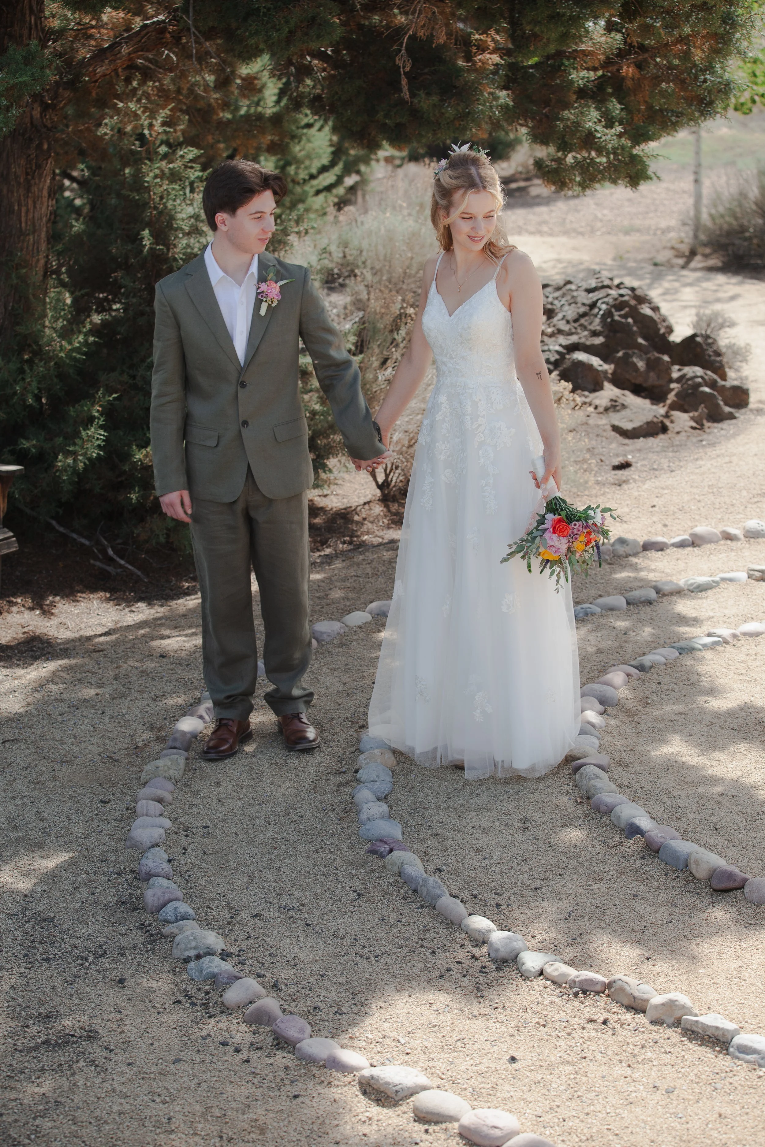 Newlyweds walking hand in hand through the High Desert landscape after their Bend, Oregon wedding