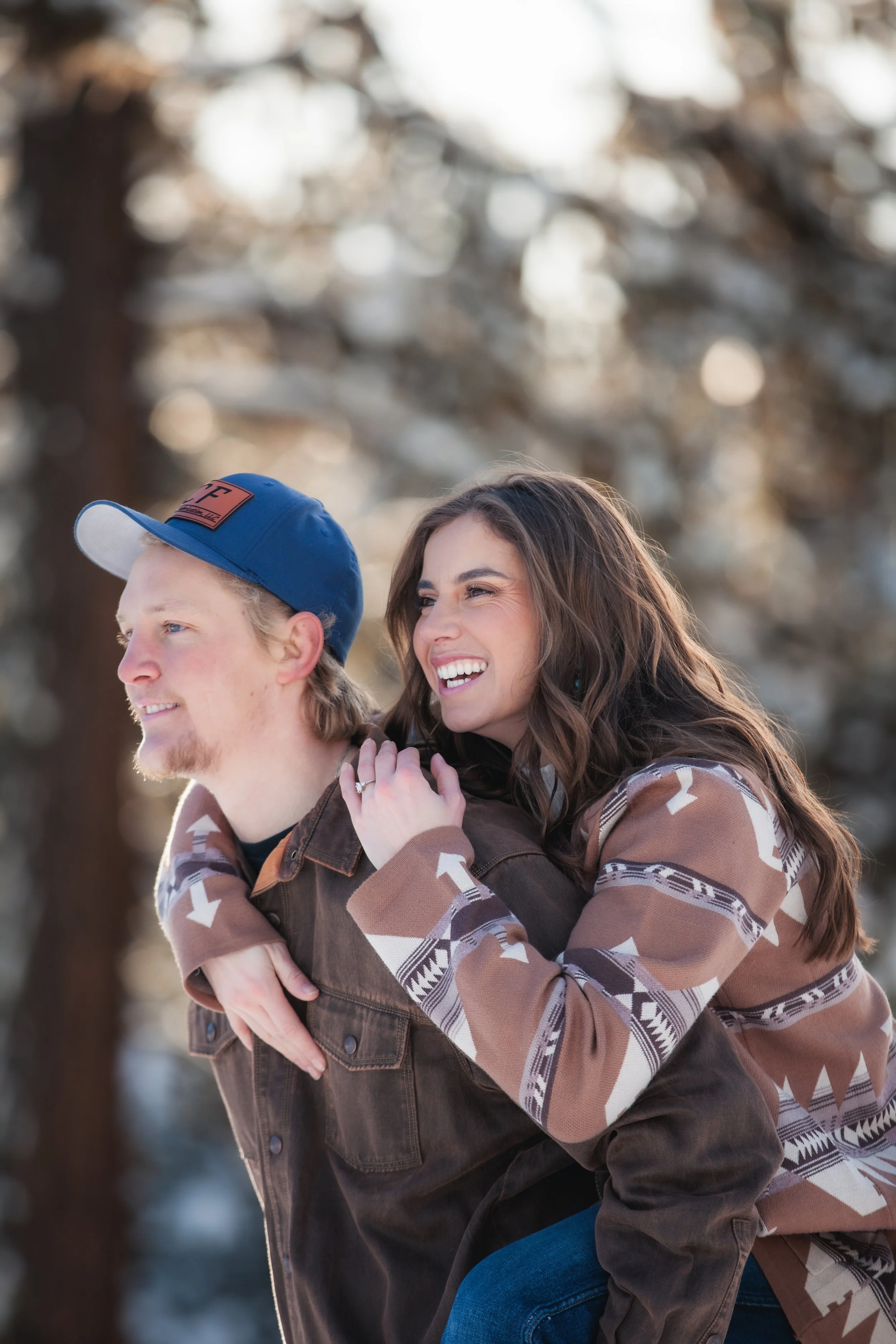 Engaged couple laughing together in warm winter sunlight during their McCall, Idaho engagement photos.