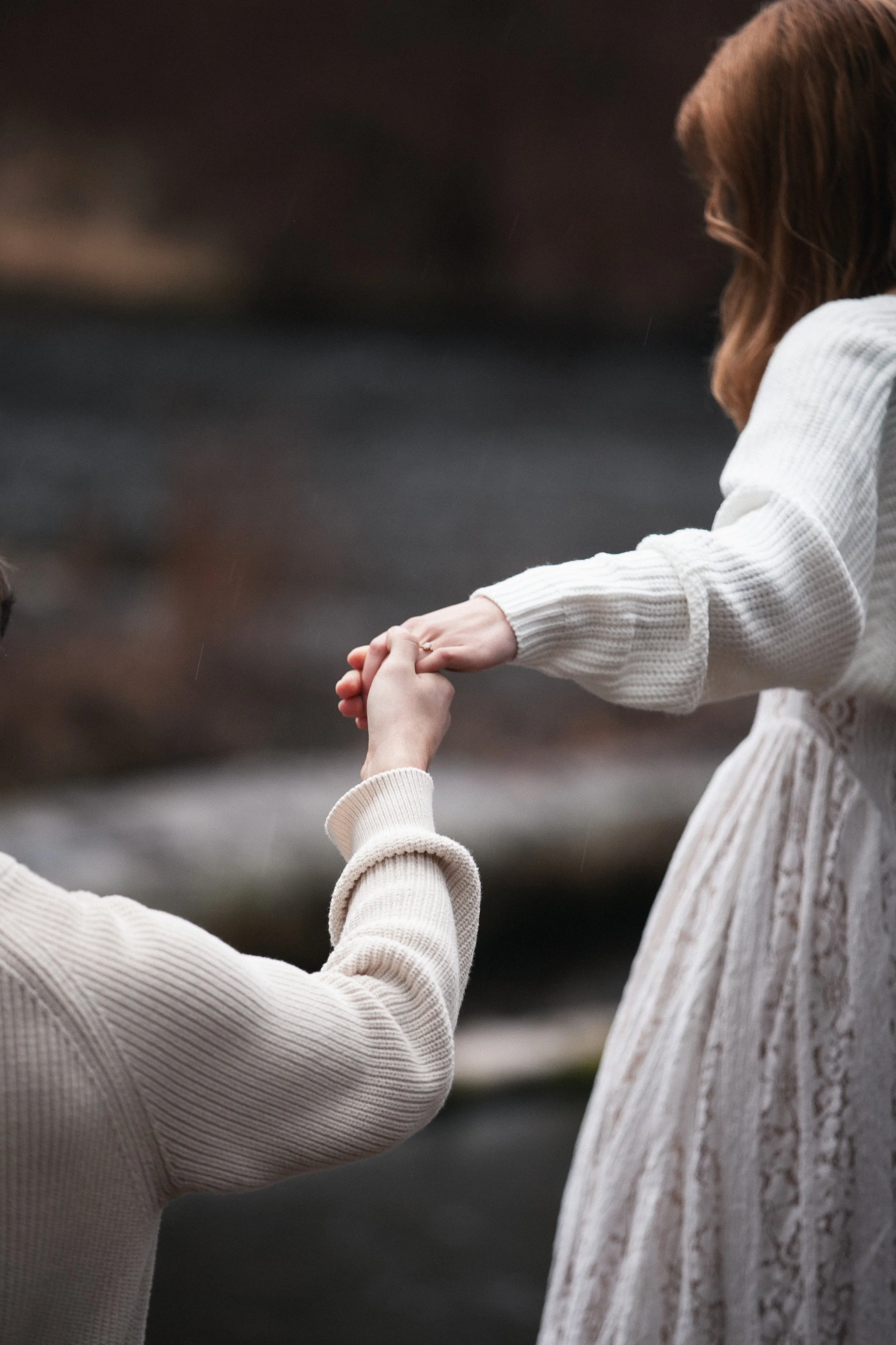 Bride and groom reaching for one another during romantic forest engagement photos near Camp Sherman, Oregon.