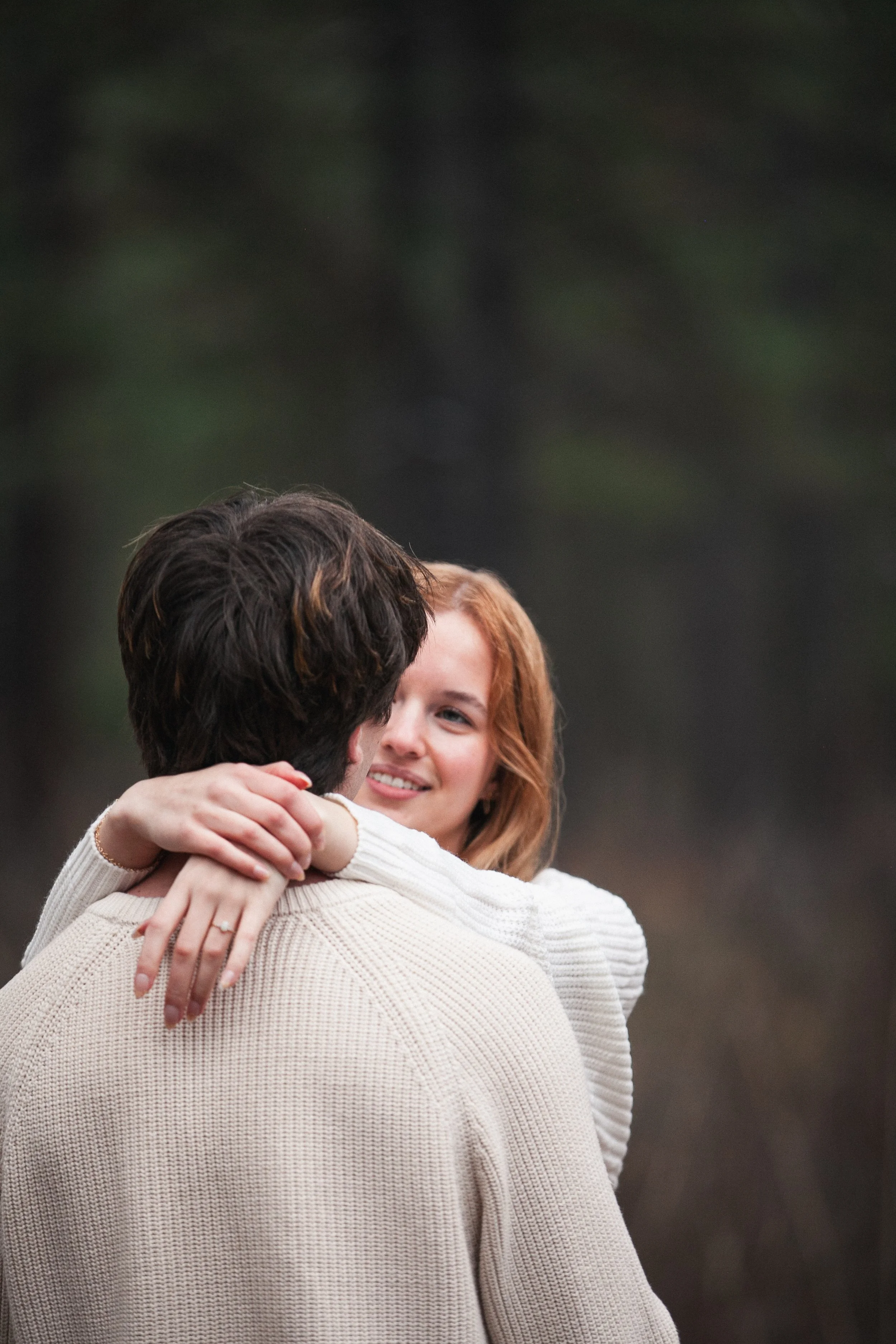 Candid engagement portrait of a bride and groom laughing together in the pine forest near Sisters, Oregon.
