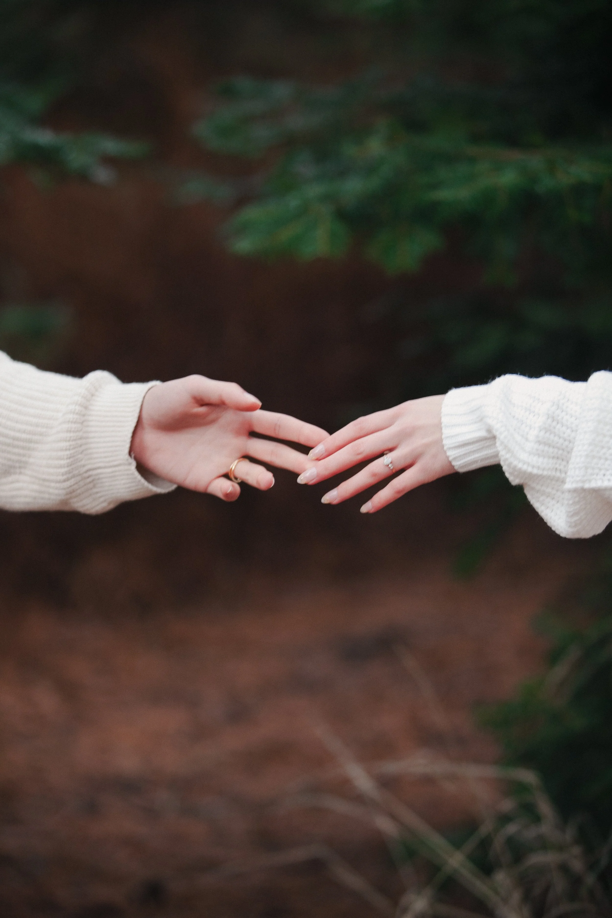 Close-up engagement photo of a bride and groom holding hands in the forest near Camp Sherman, Oregon.