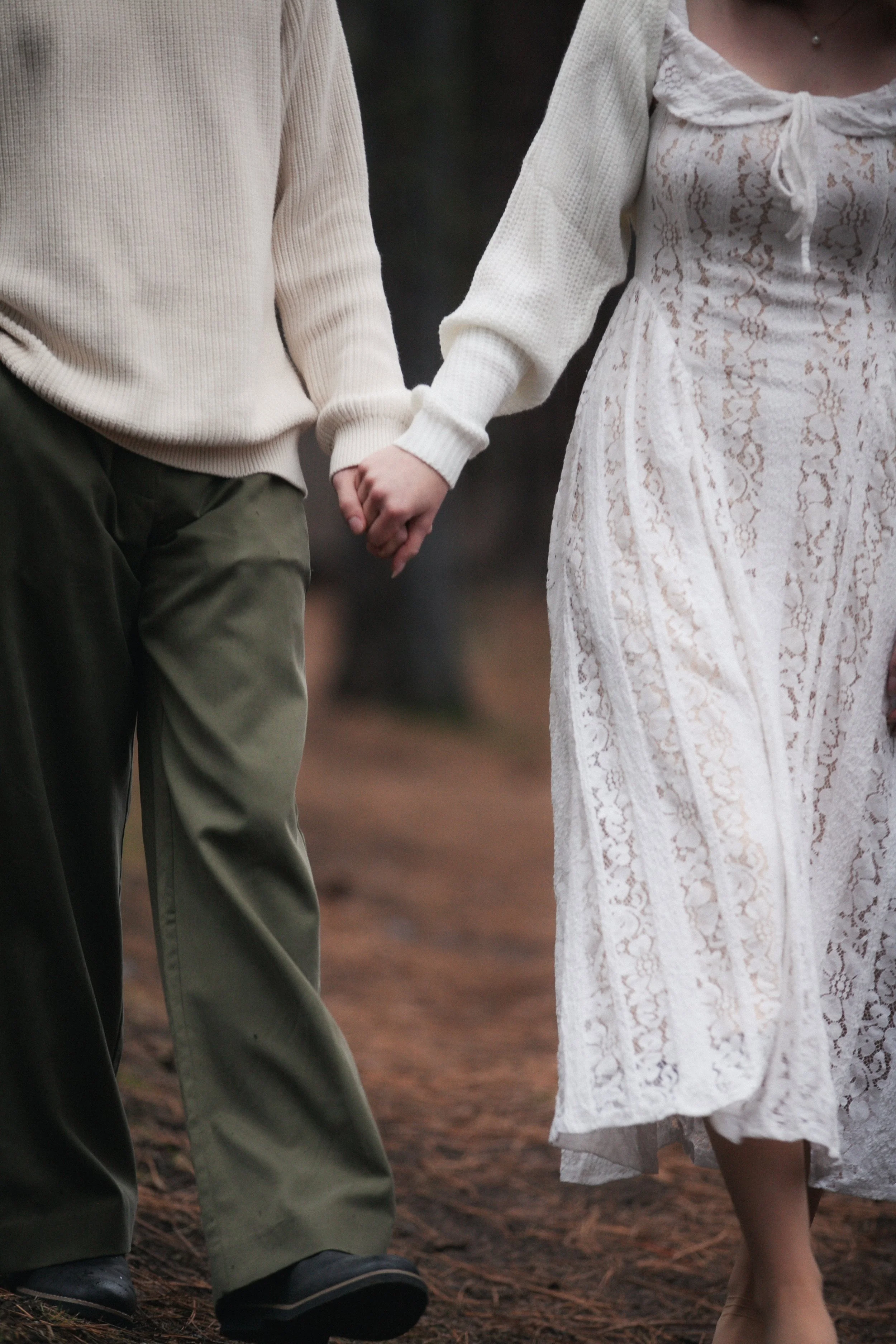Bride and groom walking through the forest in neutral winter attire during their Camp Sherman engagement photos.