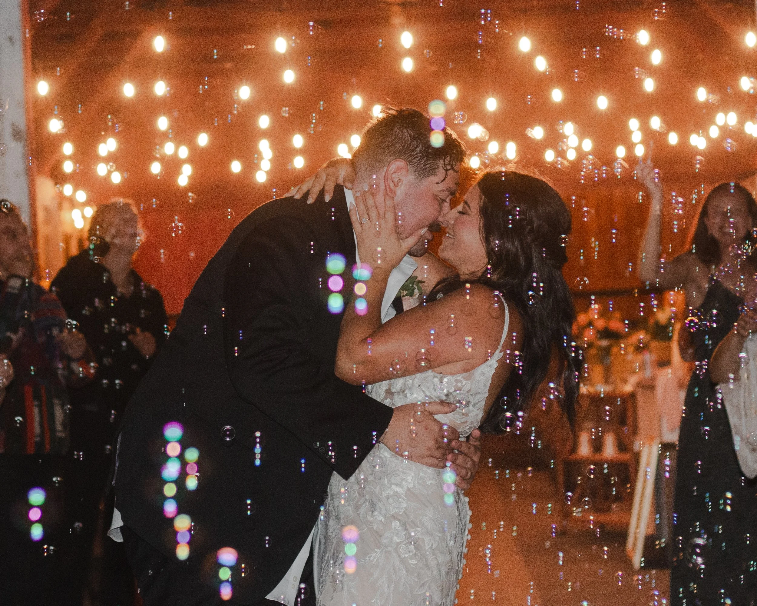 Newlyweds kissing beneath bubbles during their nighttime wedding send-off at a private ranch in Bend, Oregon