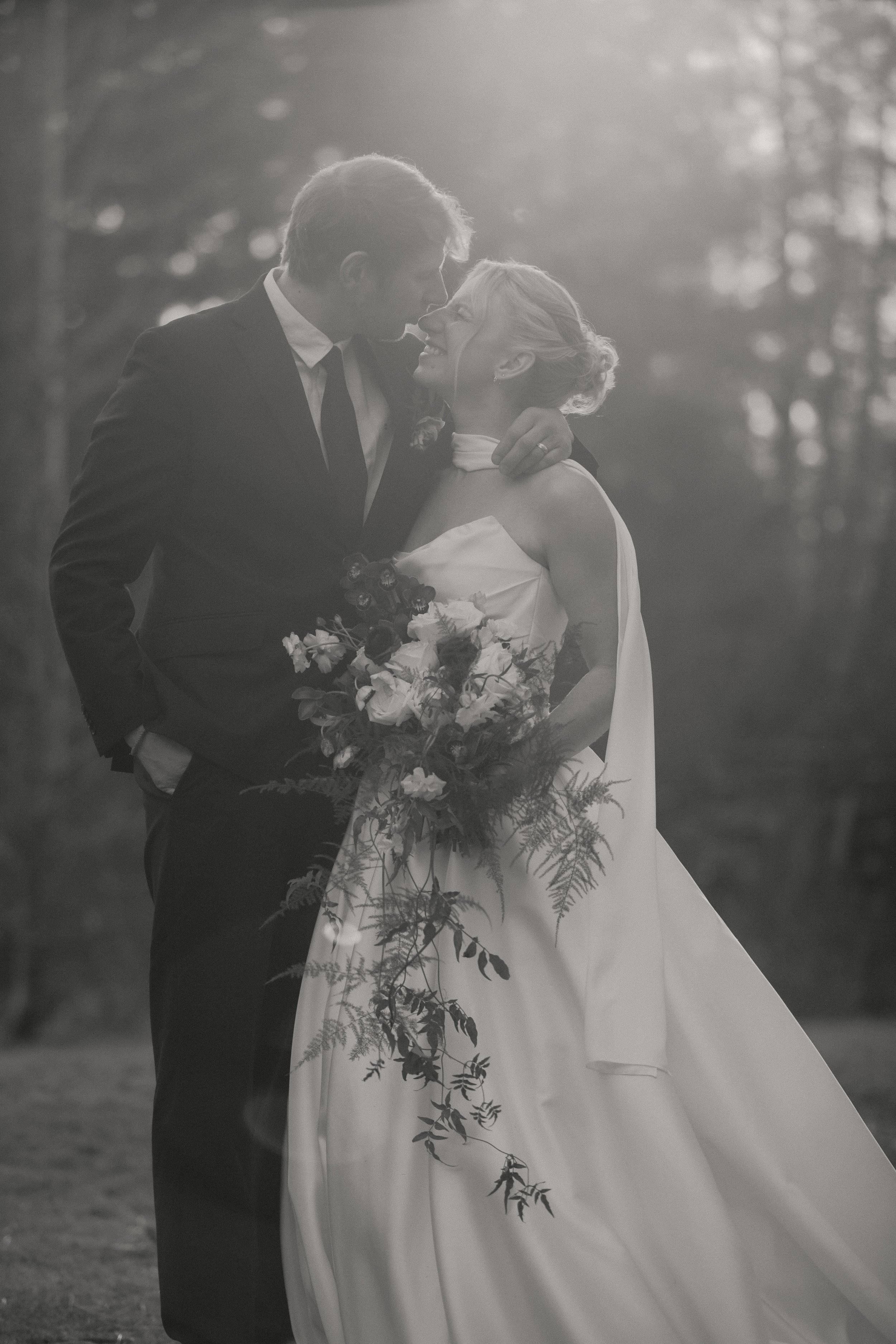 Black-and-white portrait of a bride and groom surrounded by the forest near Camp Sherman, Oregon.