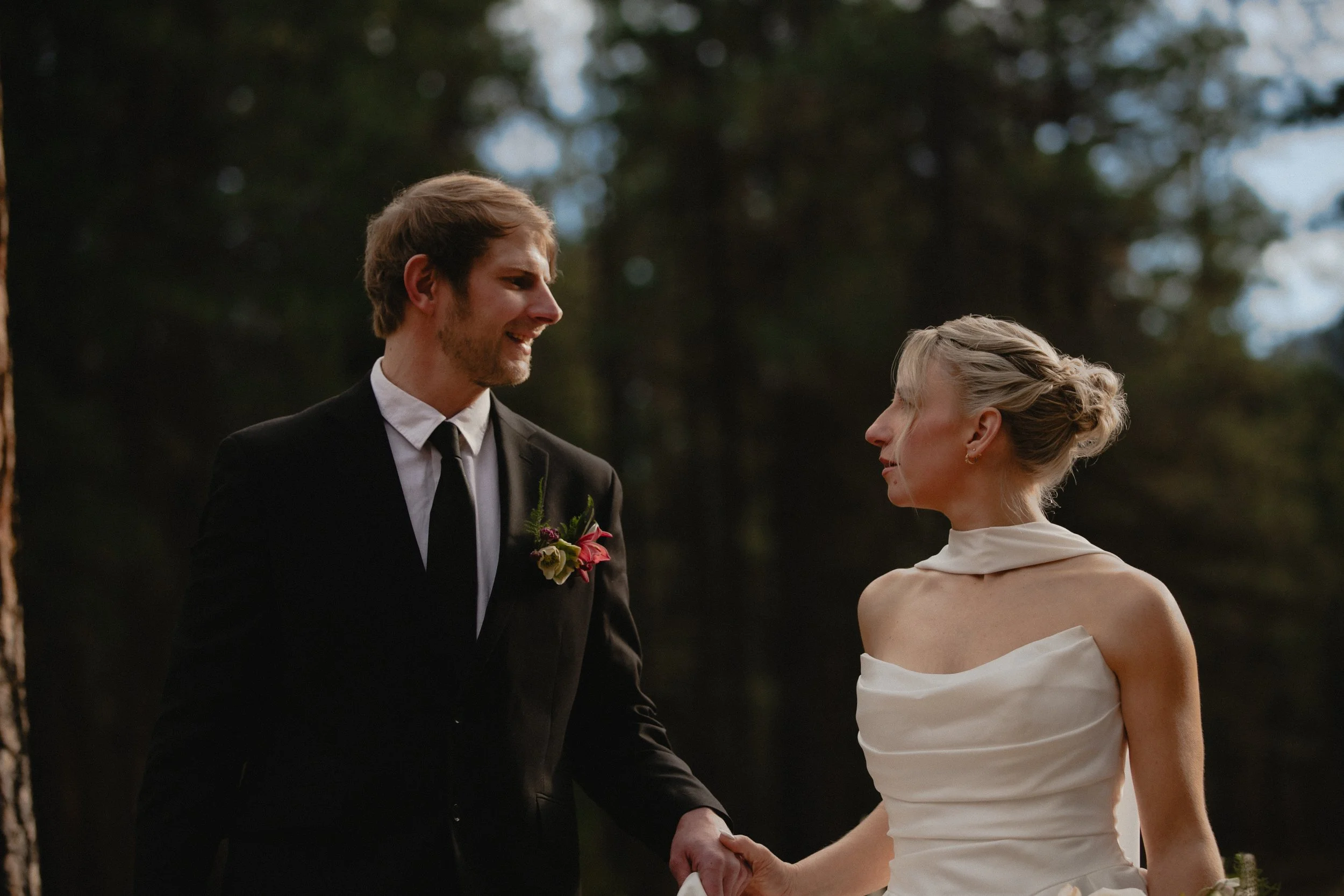 Romantic portrait of a groom lifting his bride beside the water at Lake Creek Lodge.