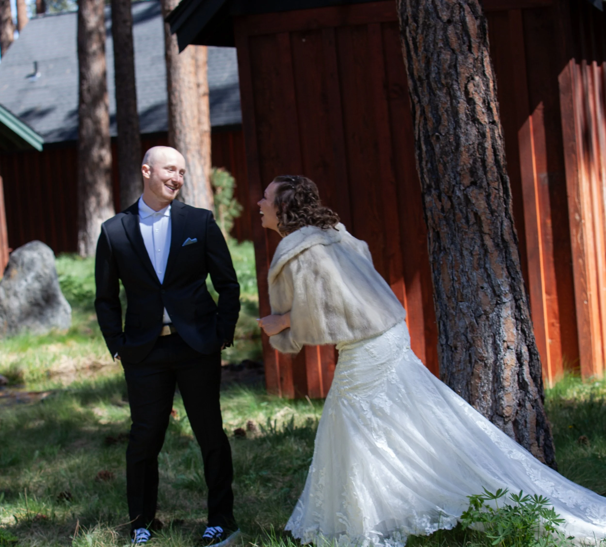Bride and groom embracing beneath towering ponderosa pines. Sisters Oregon. First Look. 
