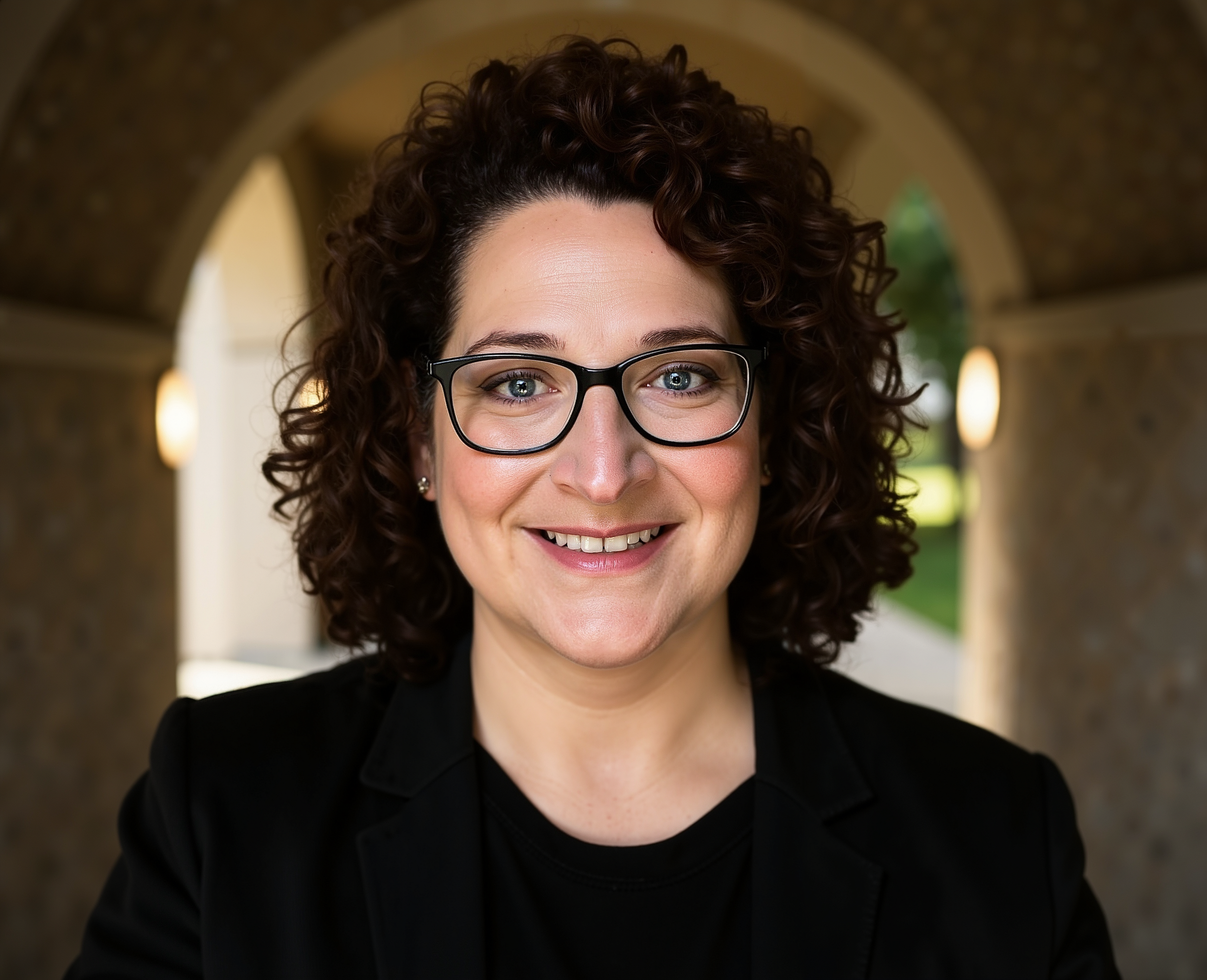 Shannon Schmit smiling at the camera in an outdoor archway setting.