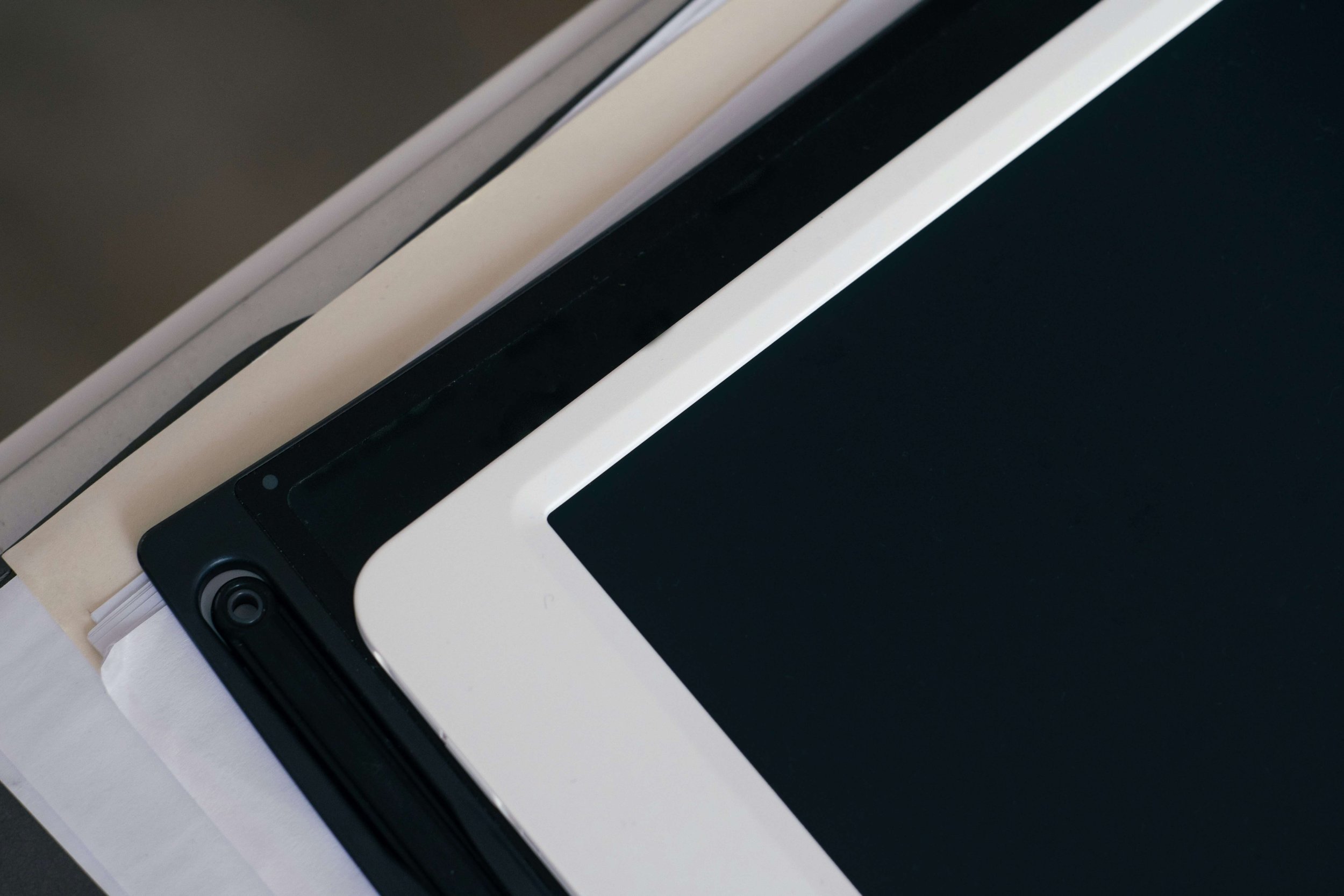 Close-up of a stack of electronic tablets and laptops with black and white screens.