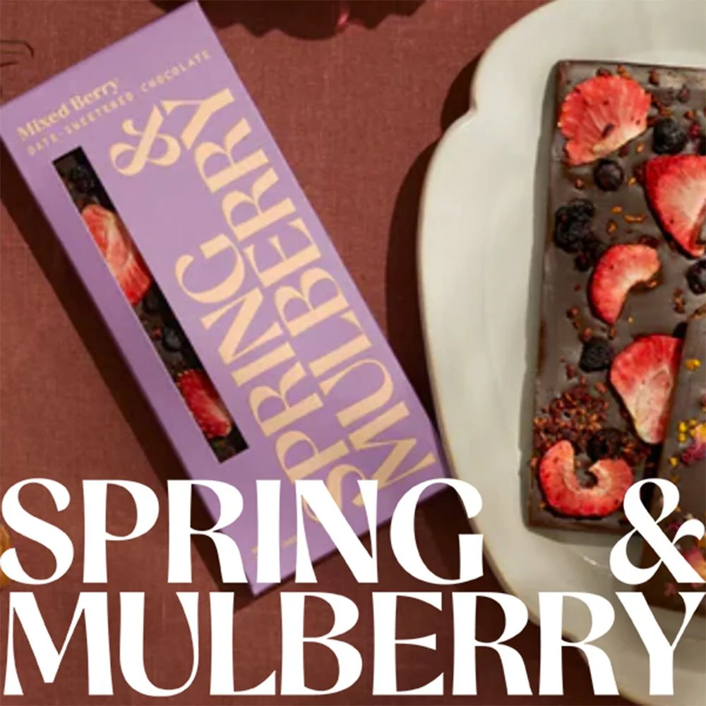 A box of mud berry bite-sized chocolates and a small dessert with strawberries, blueberries, and other berries on top.