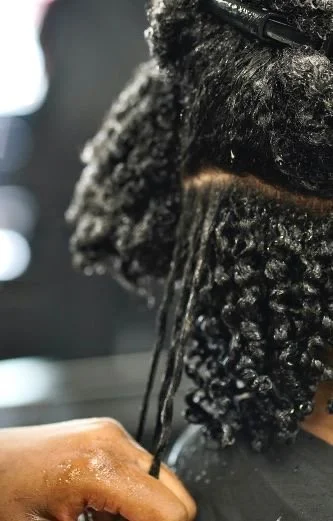 Close-up of a person getting their hair washed or conditioned in a salon, with their hair wet and curly.