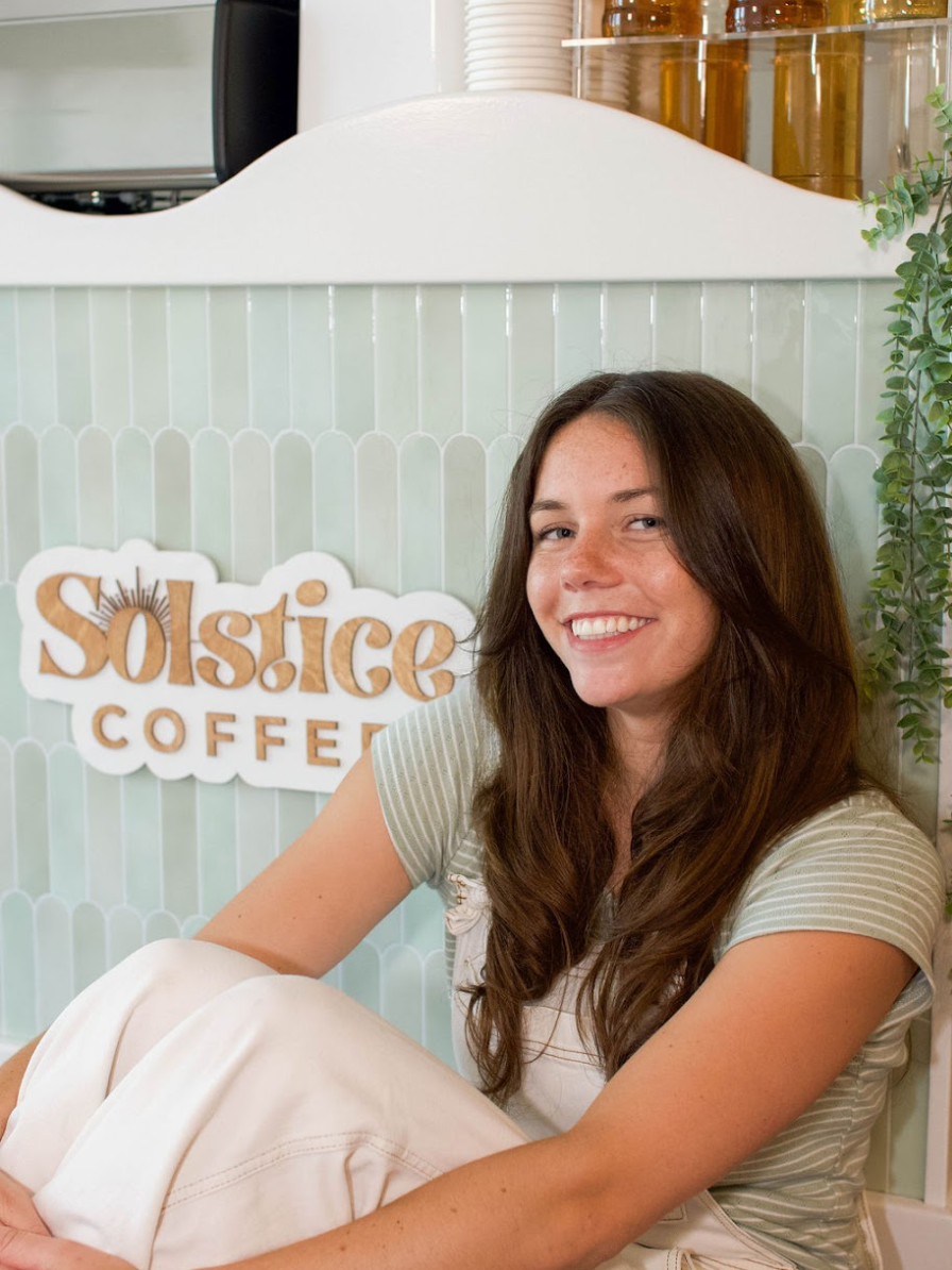 solstice coffee cart founder liza vinson sitting in front of the mobile coffee cart she built.