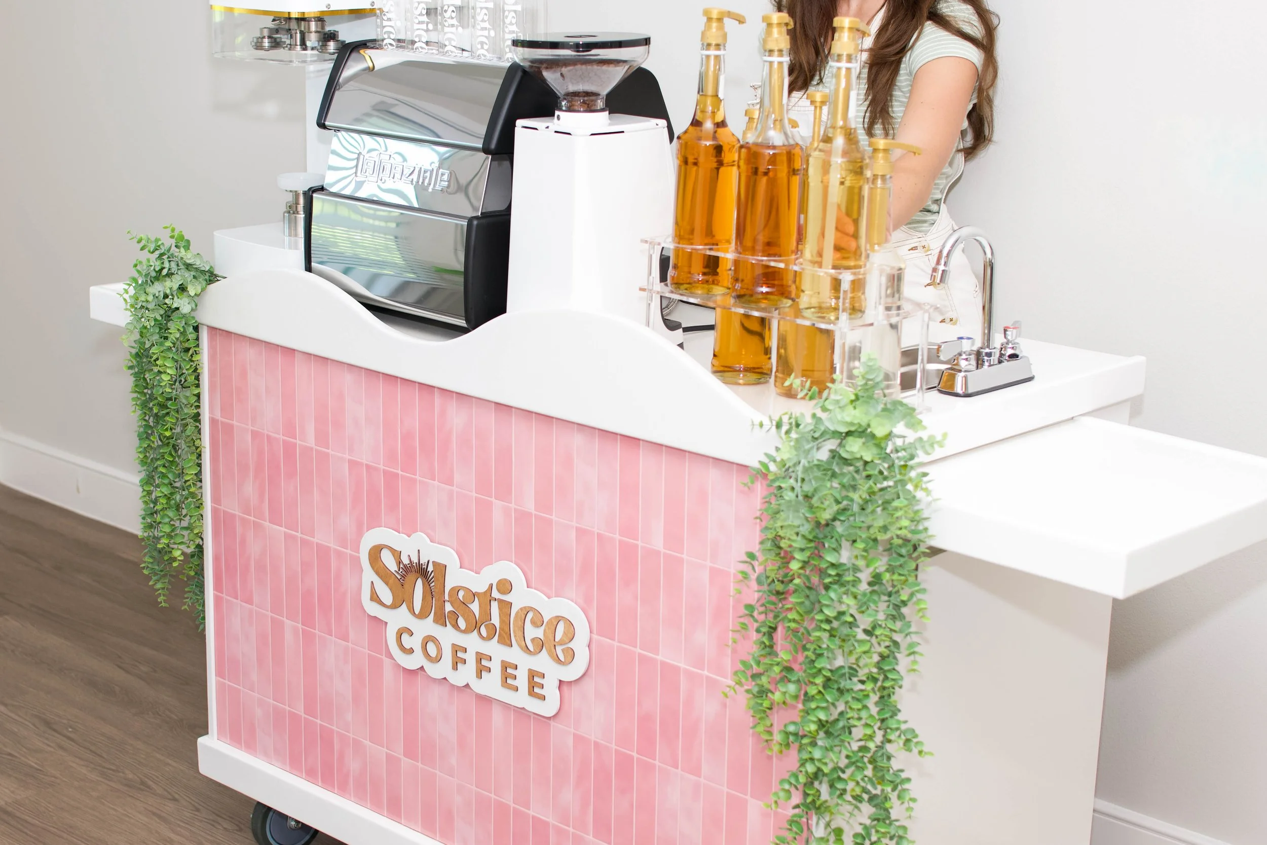 A pink mobile coffee cart with a canning machine that is used for events in texas.